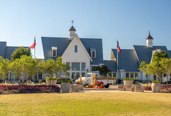 White community buildings with metal roofs, flags, and a landscaped lawn