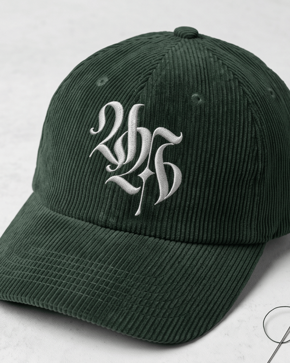 A dark green corduroy baseball cap with white embroidered initials 'LHS' on the front.