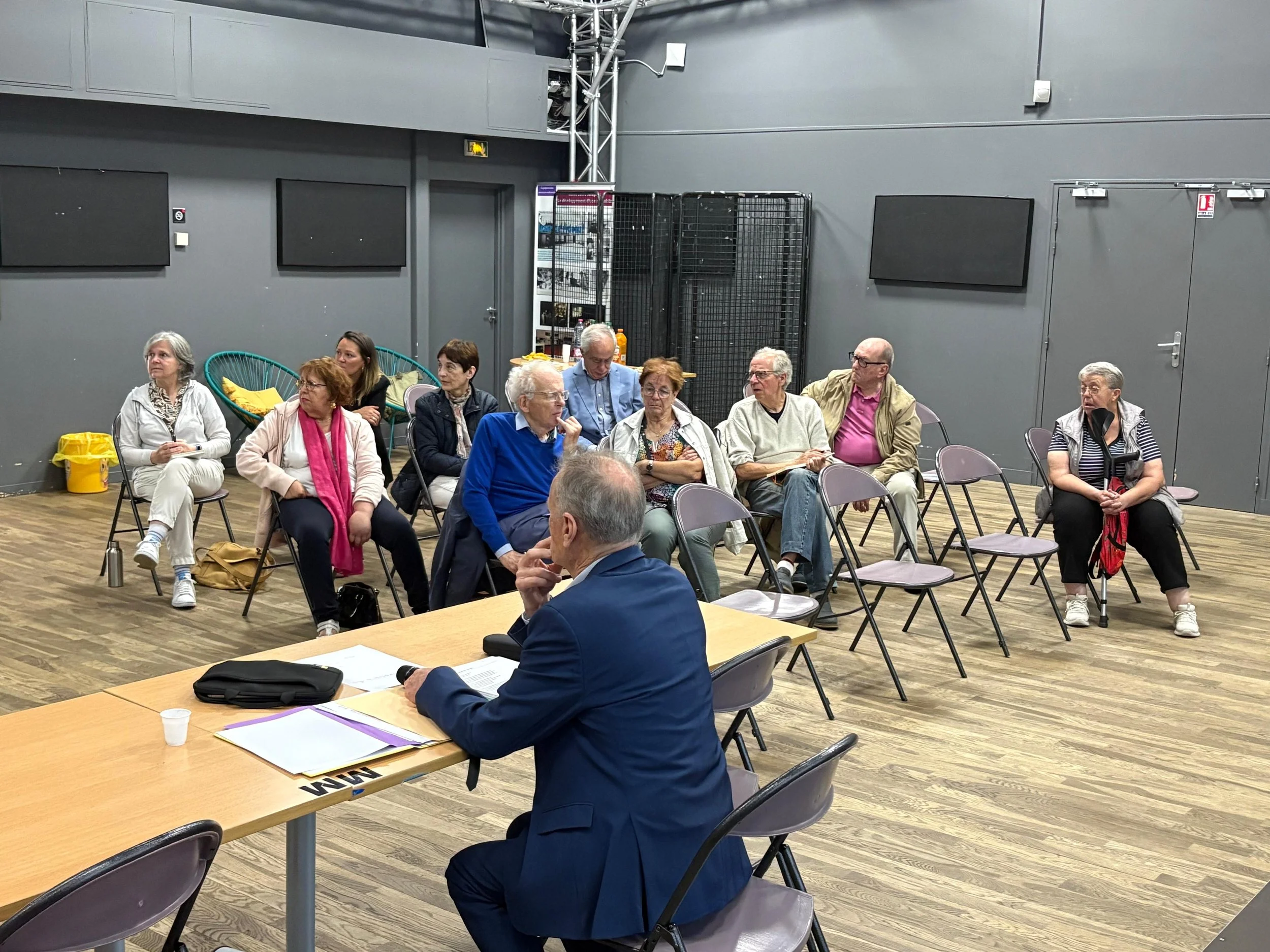 Groupe de personnes âgées assises dans une salle de conférence, participent à une réunion ou un atelier.