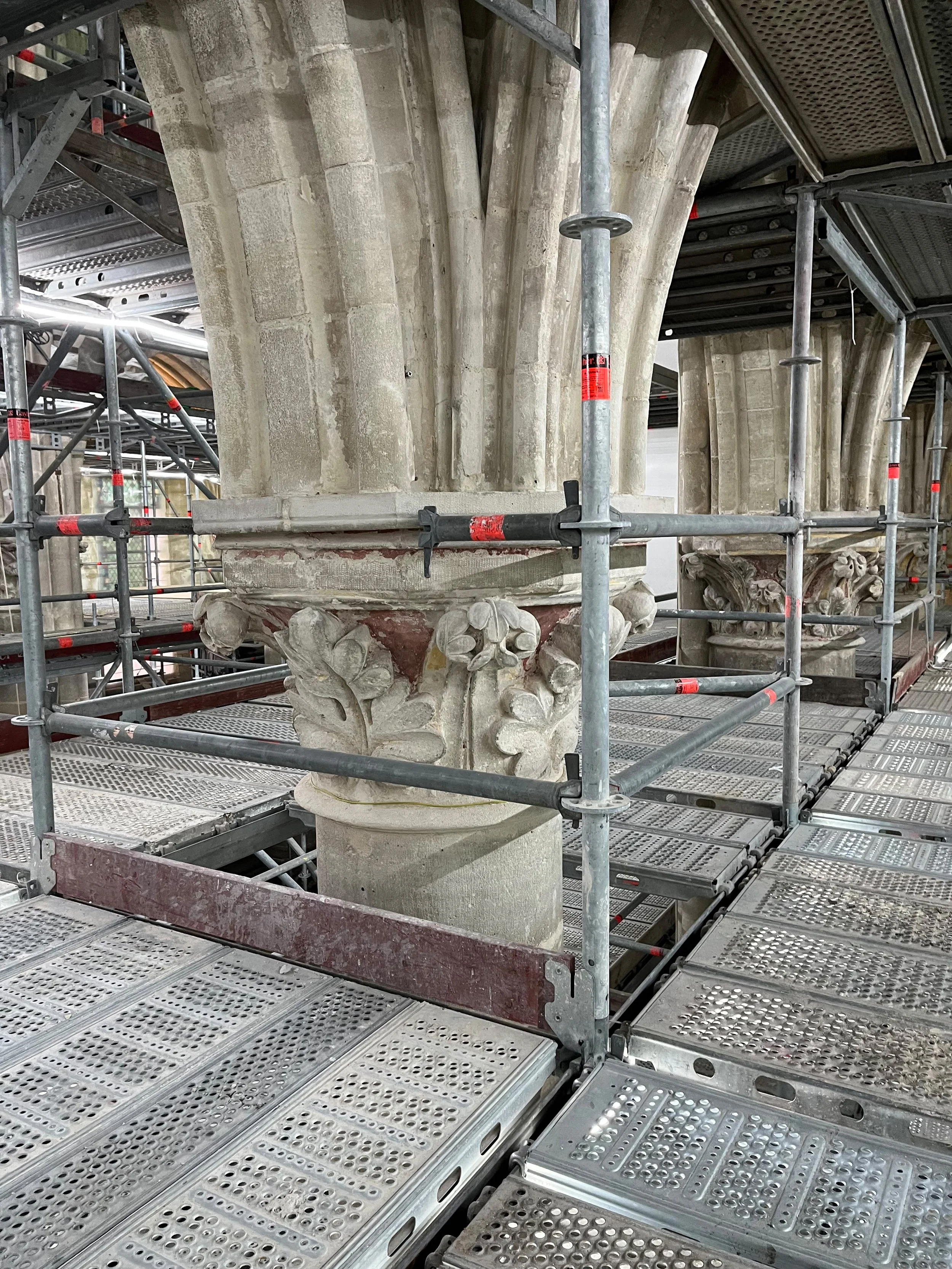 Echafaudages autour d'une colonne en pierre de style gothique ou roman, en cours de restauration ou de conservation.