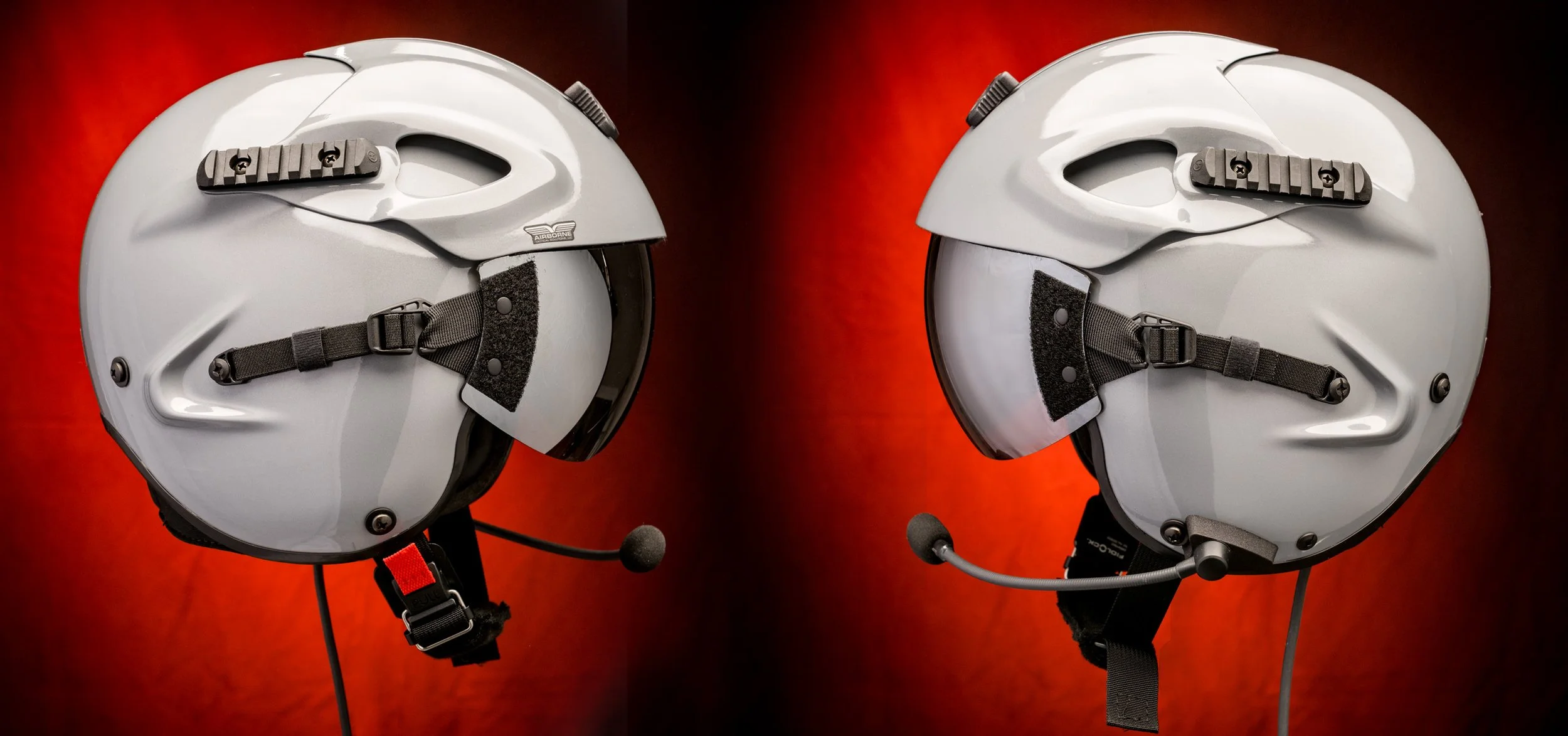 Two white motorcycle helmets with black straps and mic attachments, displayed against a red background.
