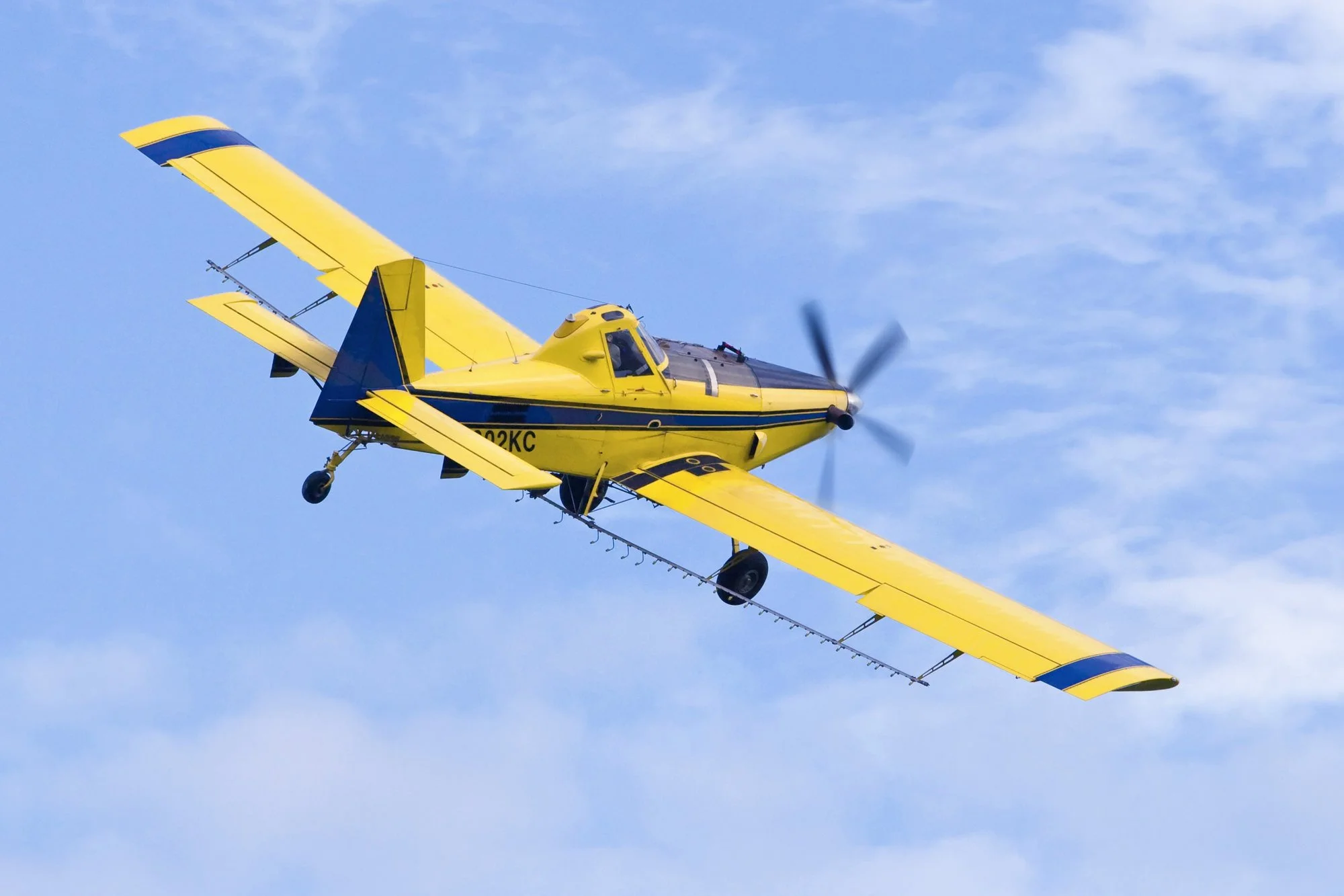 A yellow and blue helicopter flying in a clear blue sky.
