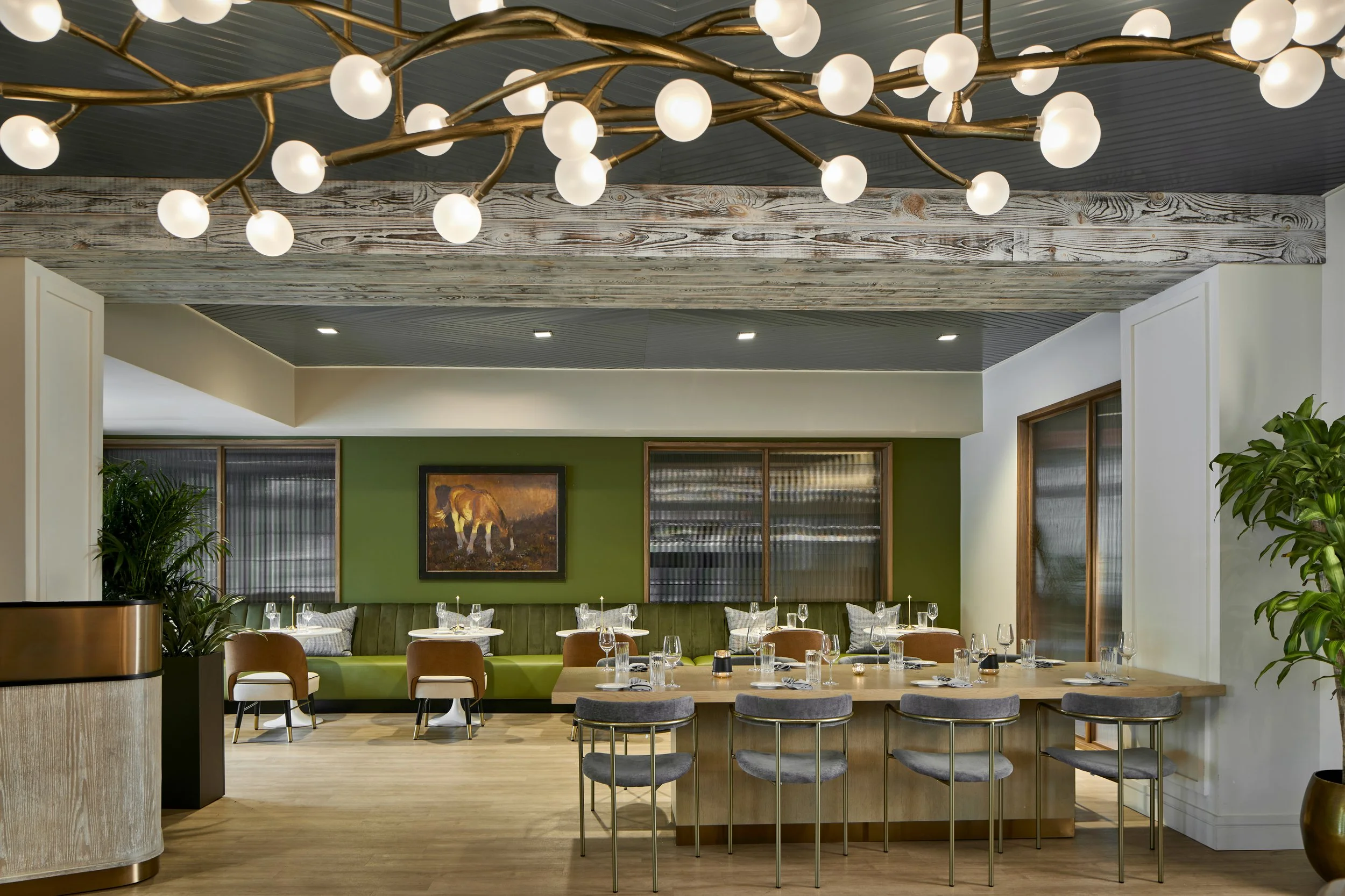Elegant dining room at Regent Restaurant & Bar featuring contemporary seating, warm wood accents, and a statement branch-inspired chandelier.