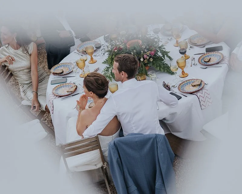 People sitting at a banquet table with elegant tableware and a floral centerpiece, celebrating at a formal event.