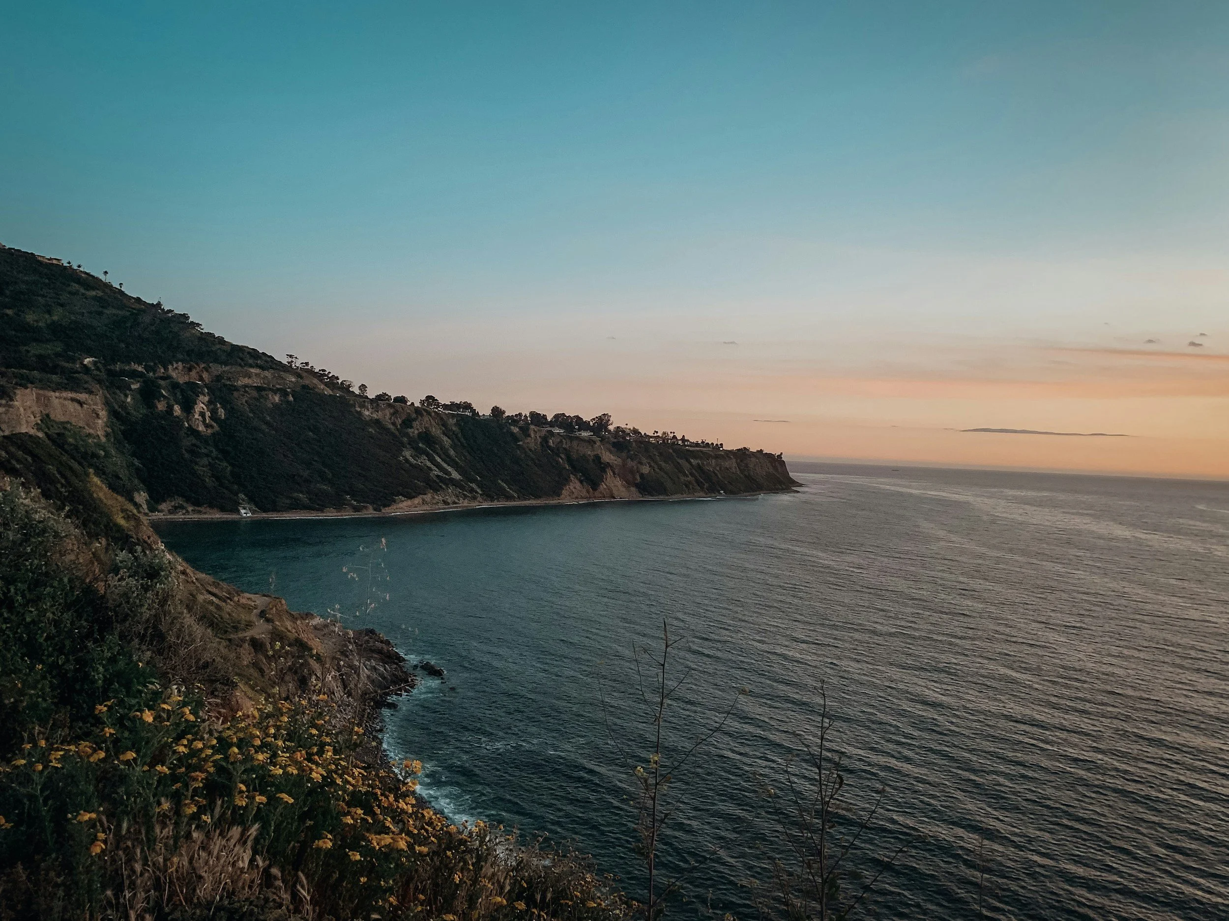 Coastal landscape of cliffs and ocean during sunset with a colorful sky.