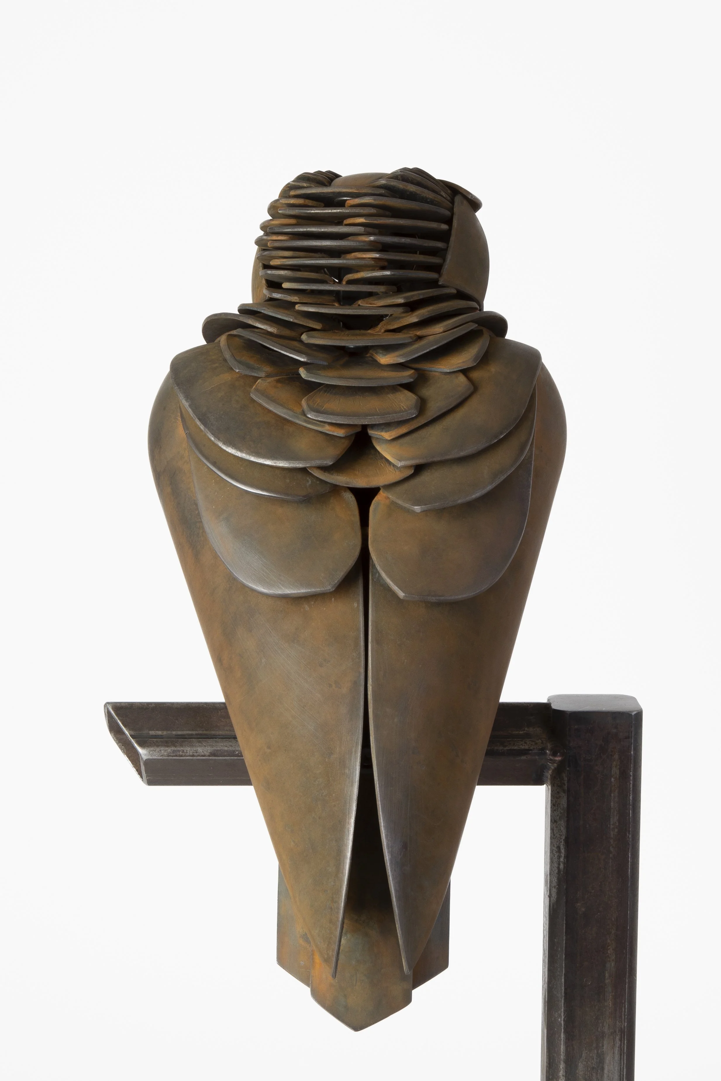 Bronze sculpture of a stylized bird figure with layered, petal-like back feathers, mounted on a dark wooden stand.