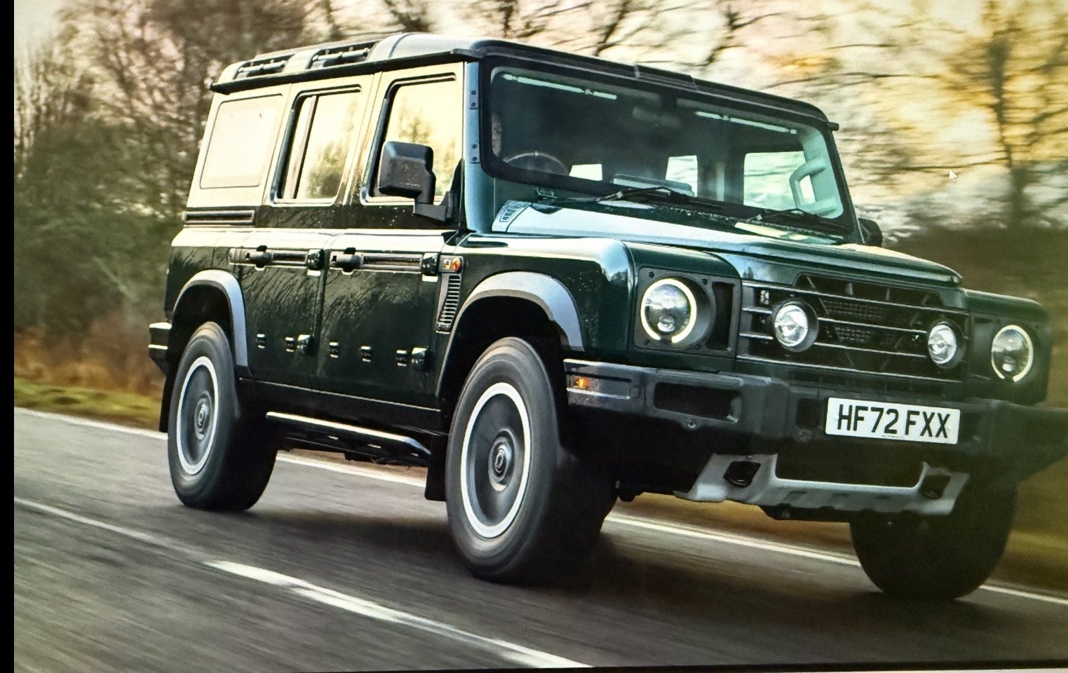 A dark green mobile spray tan service in Land Rover Defender SUV driving on a rural road in Austin Texas.