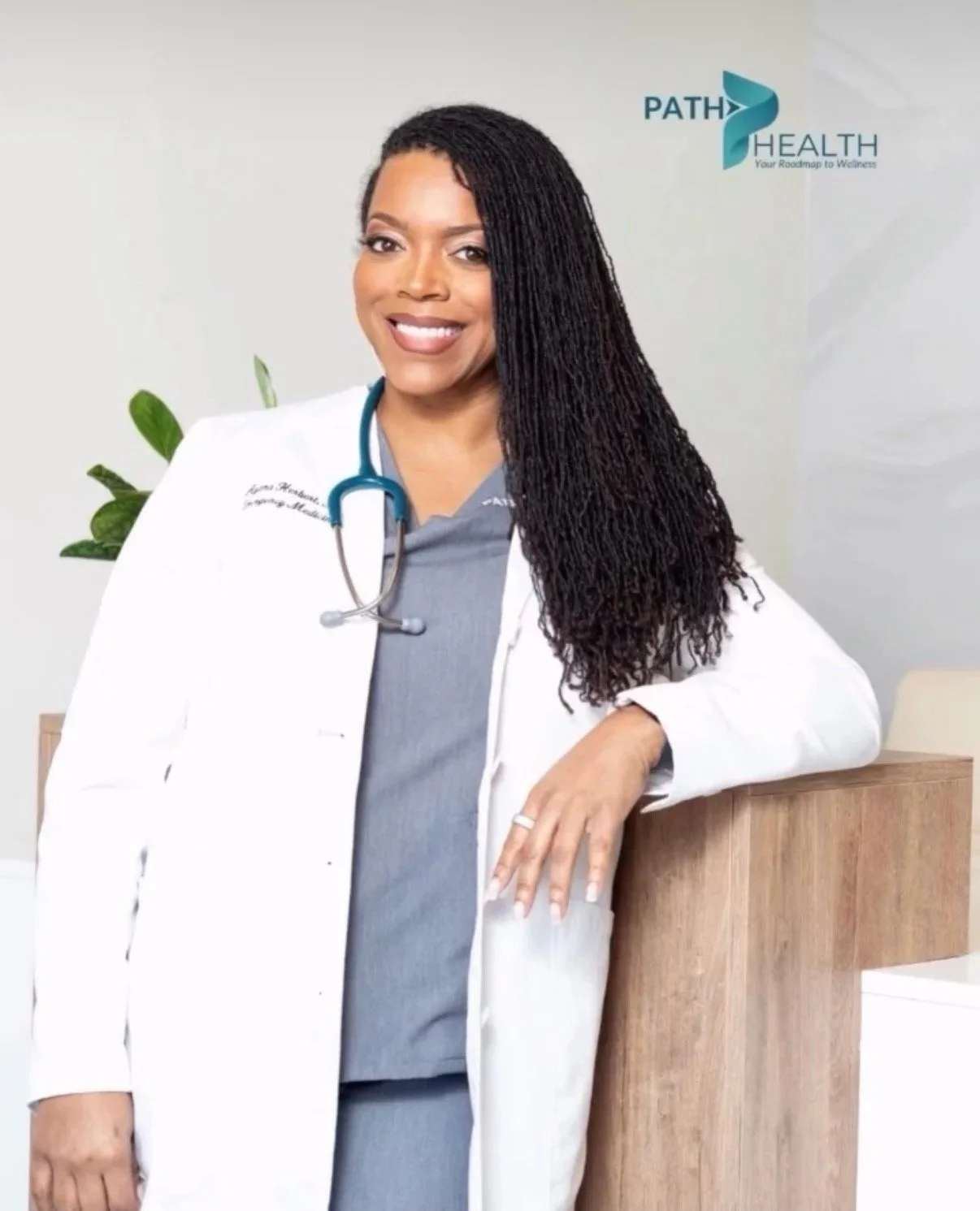 A smiling African American female doctor with long styled hair, wearing a white coat and a stethoscope, standing in a medical office with a plant and a logo that reads "Path Health" in the background.