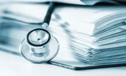 A stethoscope placed on top of a stack of papers or documents.