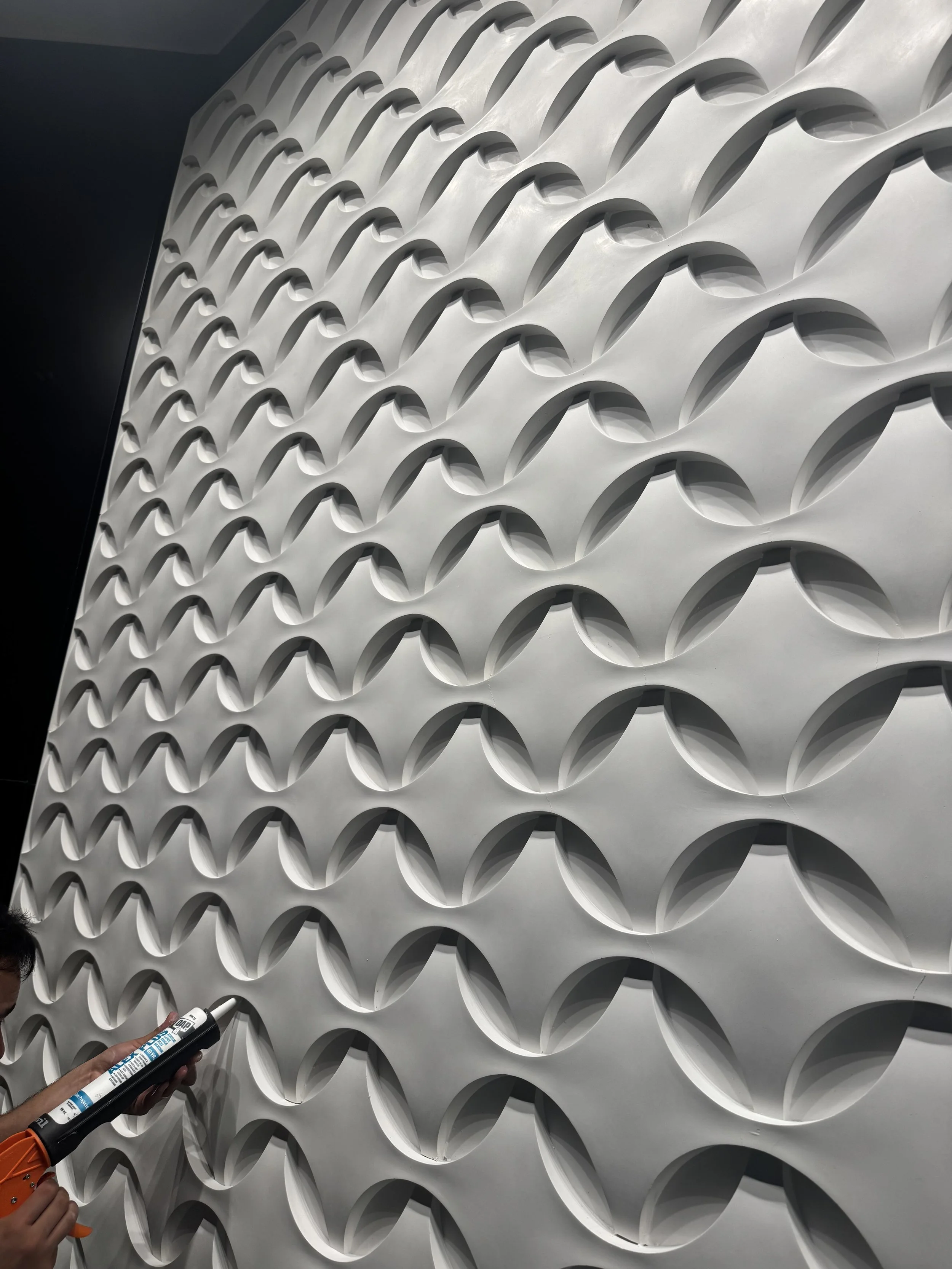 Close view of white Jesmonite facade panels with repeating sculptural relief.