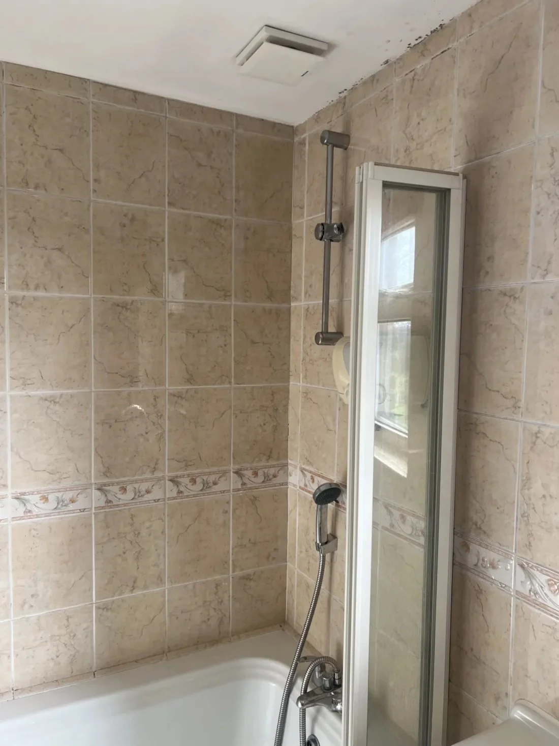 Old shower over bath with glass screen and beige wall tiles showing signs of age before renovation in a Halewood bathroom