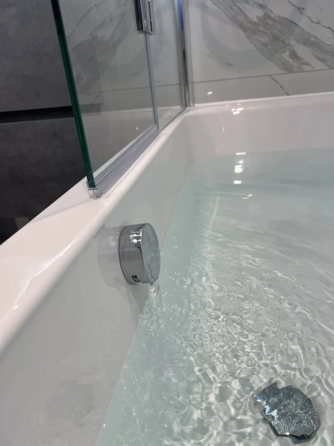 Close-up of bath overflow filler with running water in a newly installed modern bathroom in a Halewood home