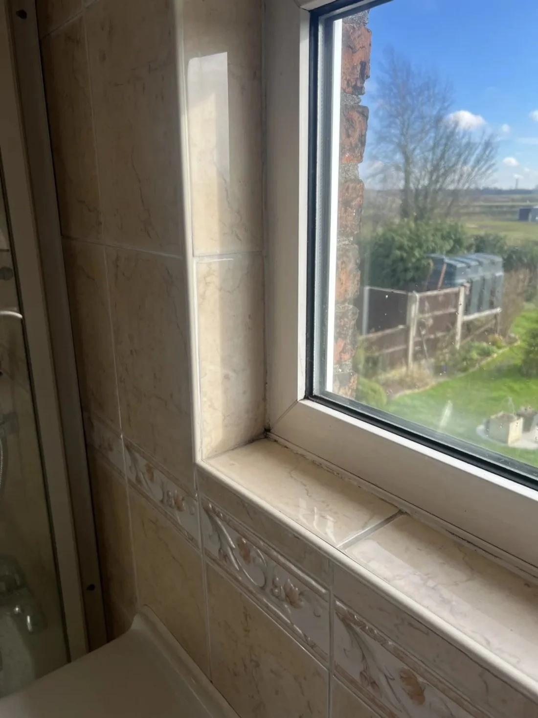 Close-up of bathroom window with dated tiled surround and sill showing wear prior to renovation in a Halewood home