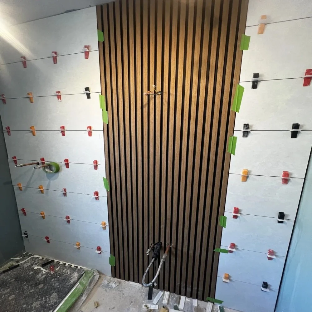 Bathroom renovation in Aigburth showing vertical wood slatted feature wall with surrounding large format tiles, spacers, and ongoing installation work