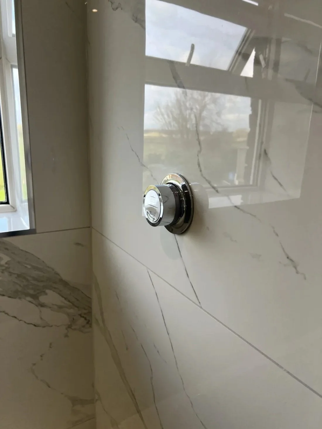Close-up of modern thermostatic shower control on marble effect wall panel in a newly renovated Halewood bathroom