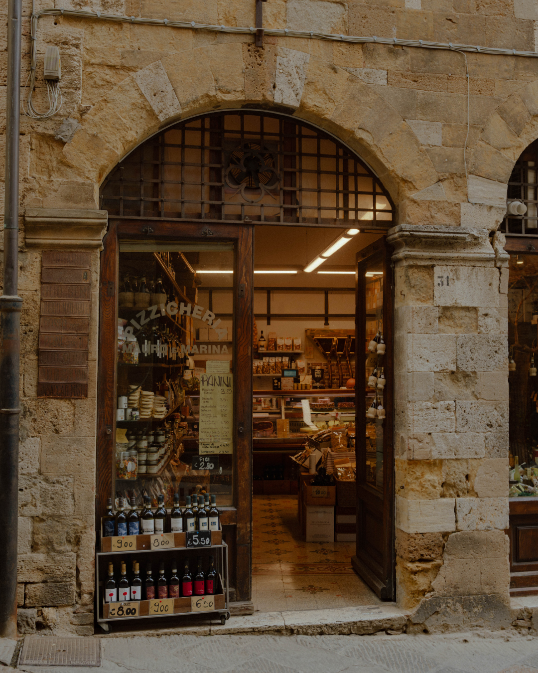 Une boutique de produits locaux et alimentaires dans une ancienne bâtisse en pierre, avec des bouteilles de vin et des produits en vitrine.
