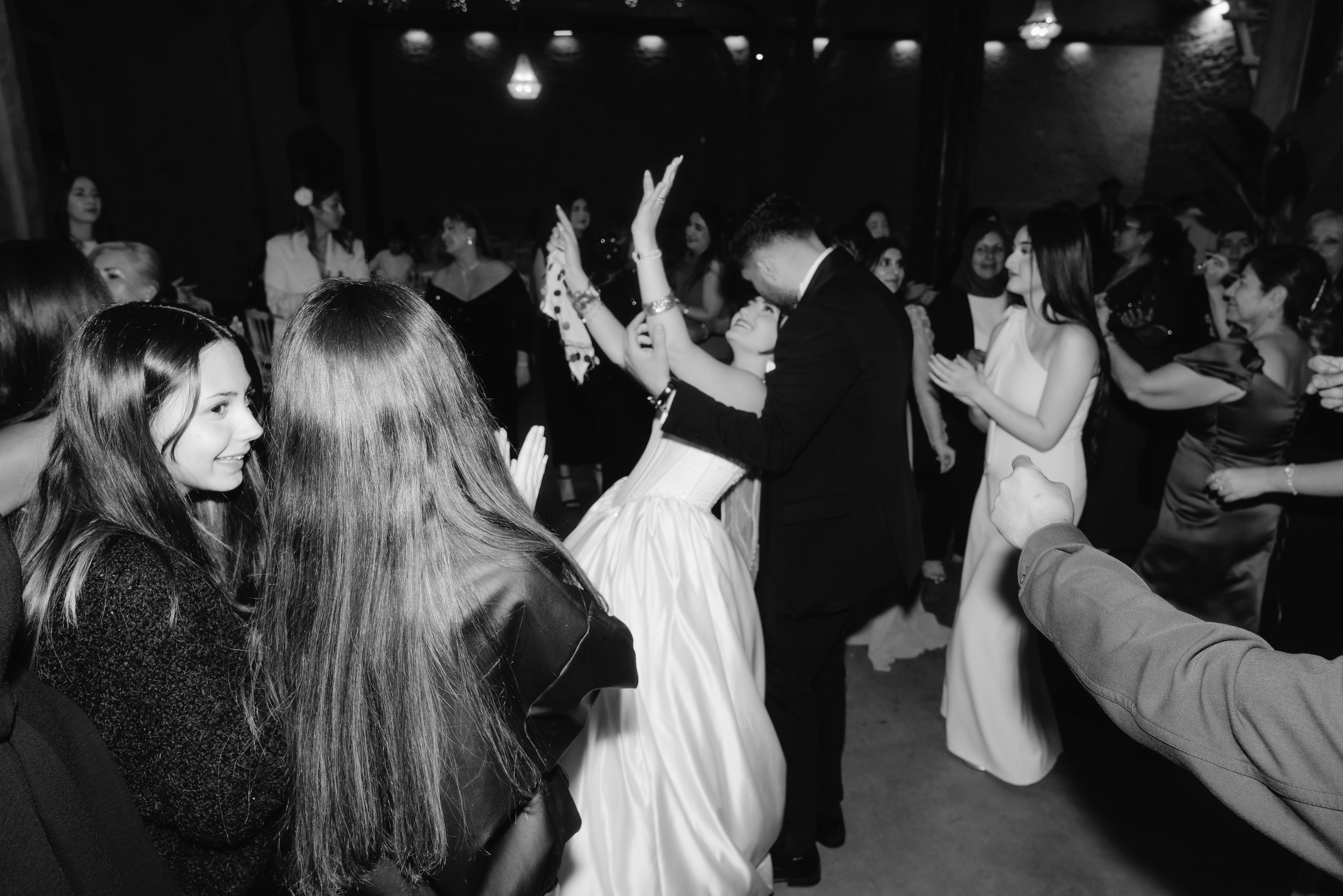 Un groupe de personnes dansant lors d'une célébration ou d'un événement festif, vu de profil, en noir et blanc.