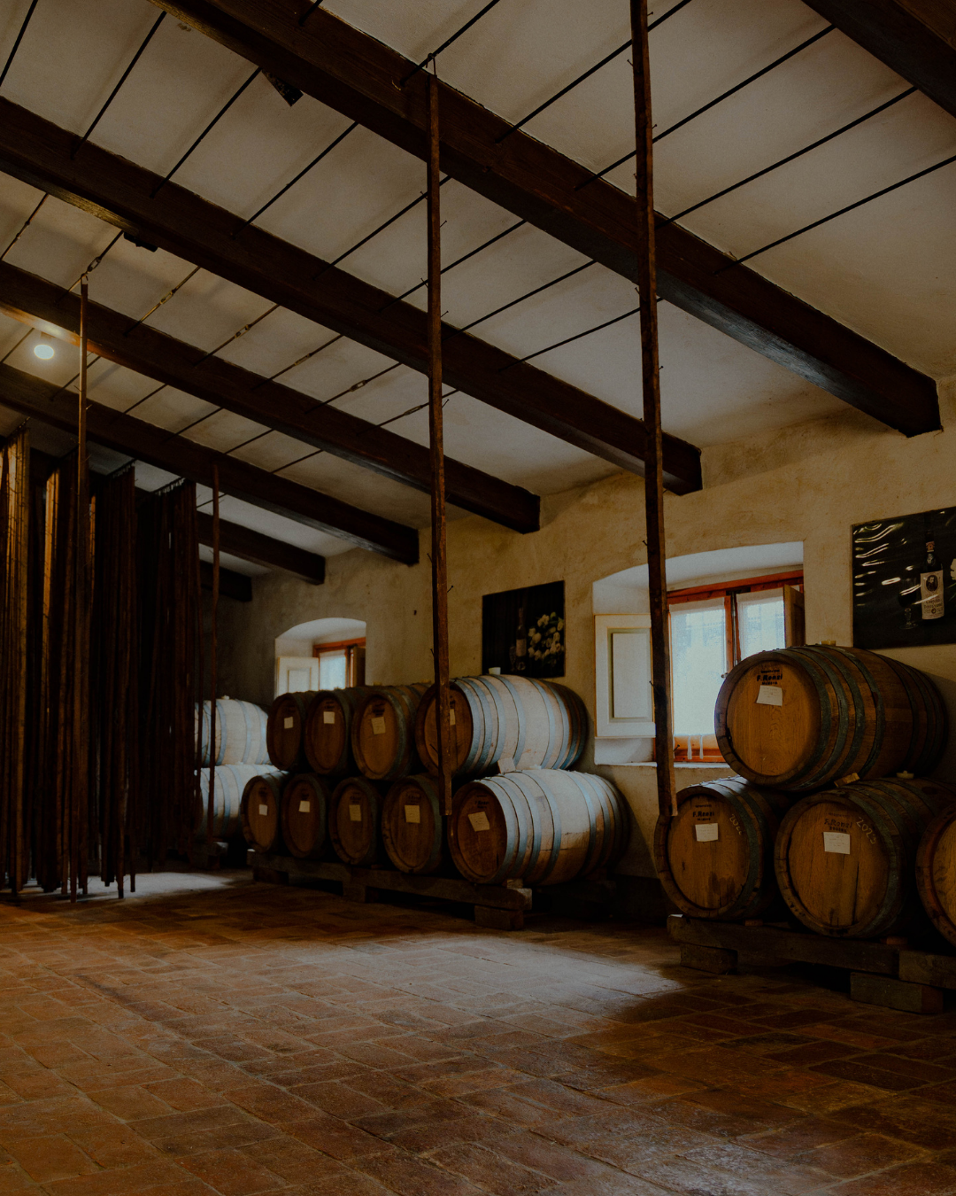 Salles de stockage de fûts de vin en bois dans une cave à vin avec plafond en bois et fenêtres, éclairage doux.