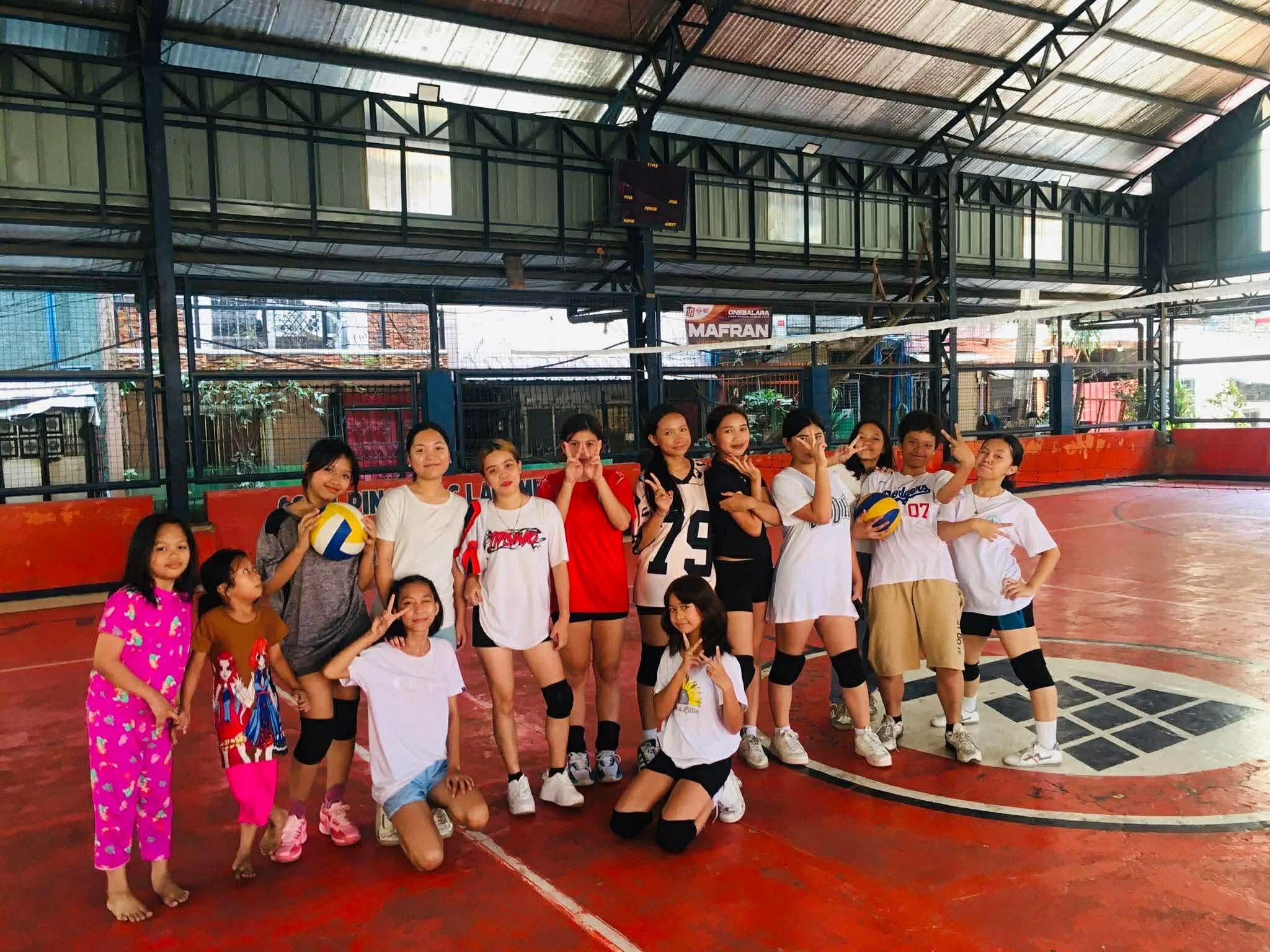 Group of young girls and women in sports uniforms posing for a photo for a Crossover event