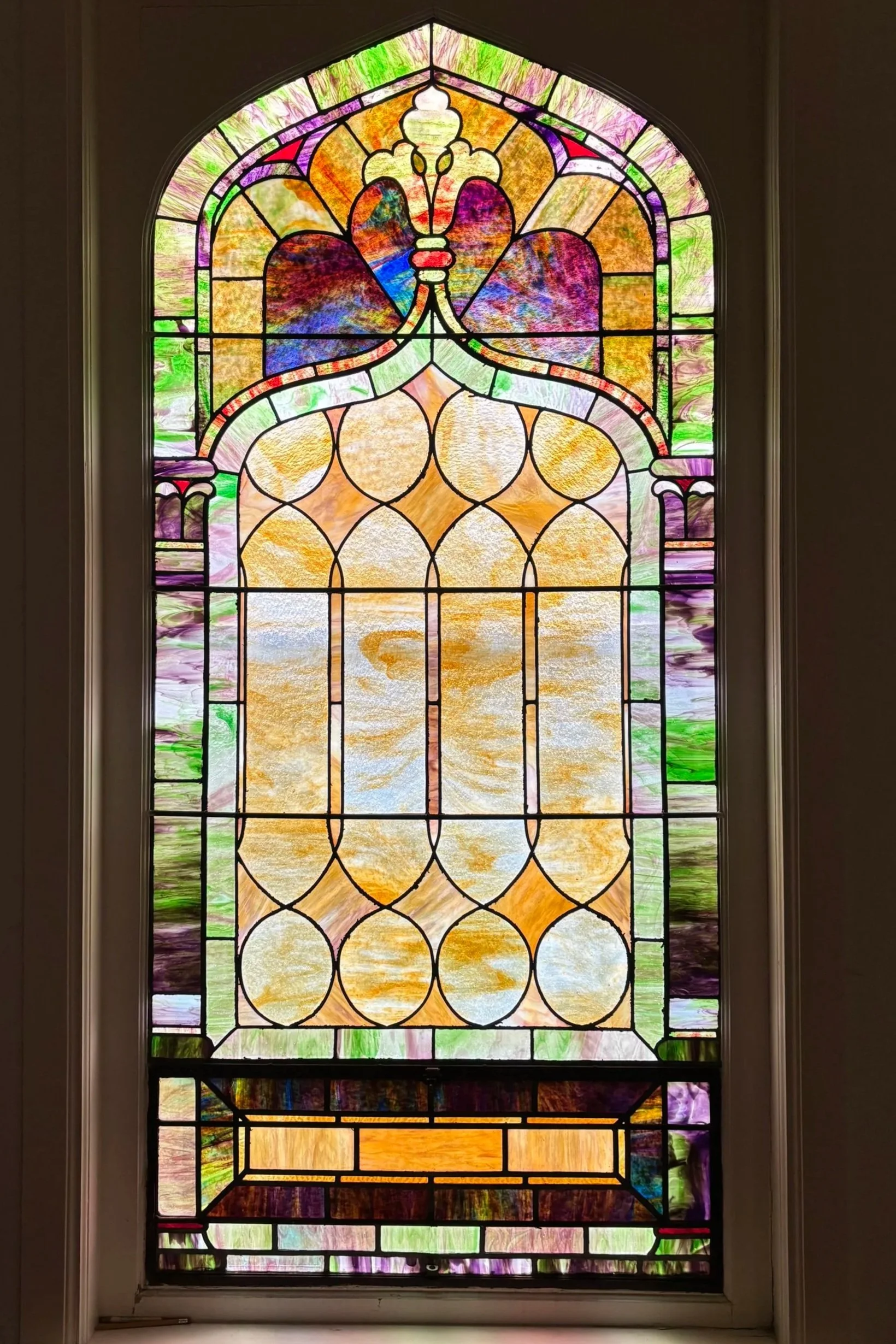 Colorful stained glass window with geometric and floral patterns.