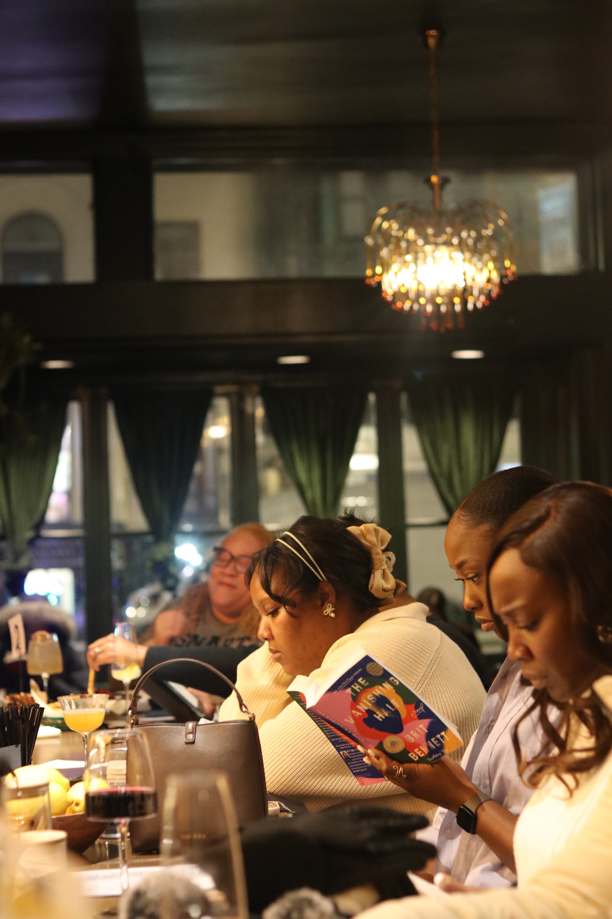 A group of women reading and enjoying cocktails while attending the Unbound event Bring Your Own Book at Shanklin Hall in Washington, DC's Adams Morgan neighborhood.