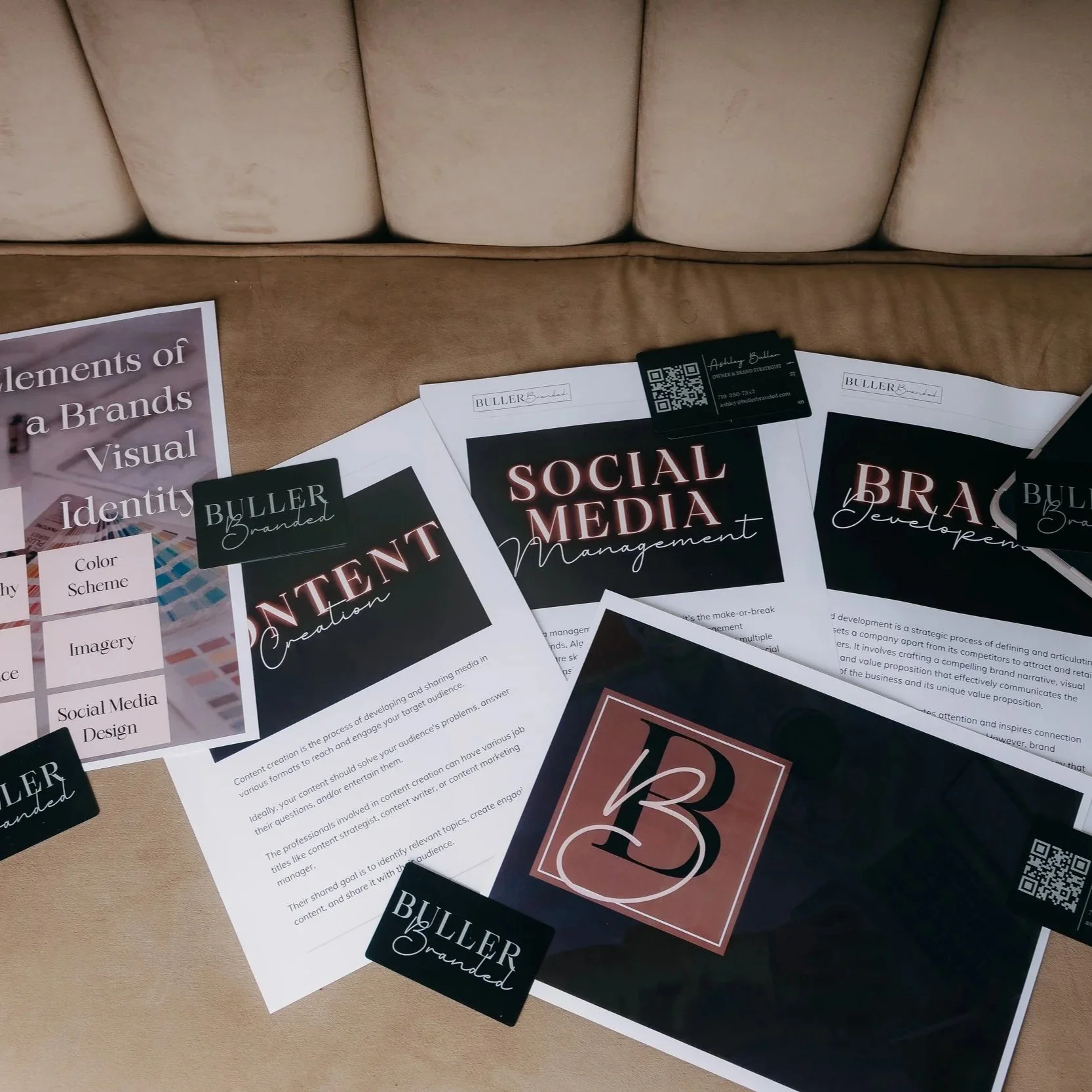 Collection of printed materials about branding elements, including social media management, content creation, and brand development, with black, pink, and white color themes, business cards, and QR codes.