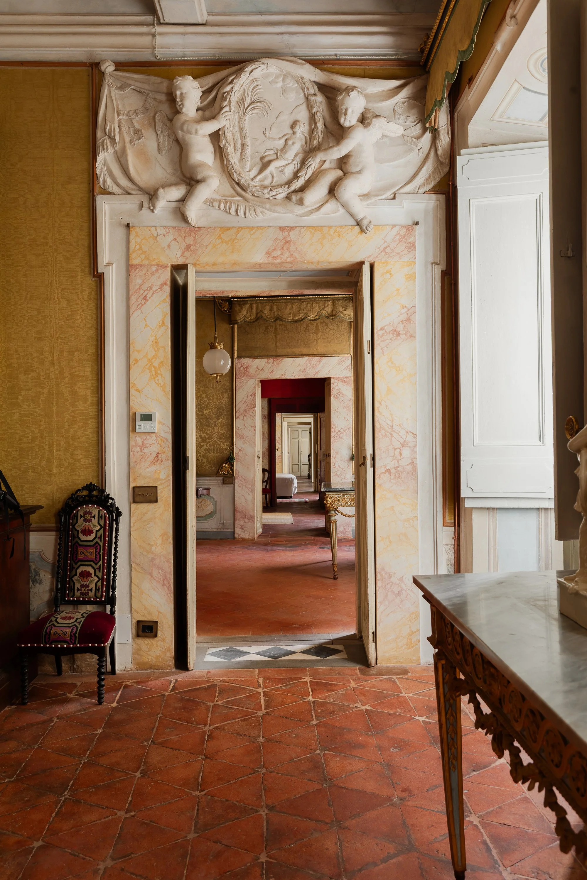 View through a series of interior doors in a grand, historic building, with ornate decoration and classical sculptures.