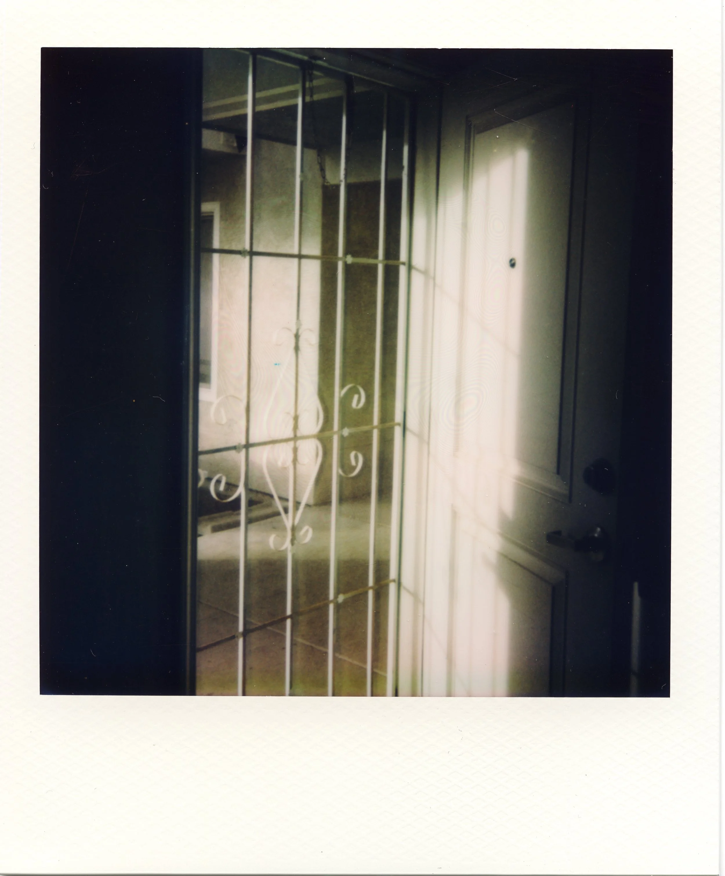 An empty room with metal framing for a wall or door, with a window letting in natural light, and a closed white door with a small round doorknob.