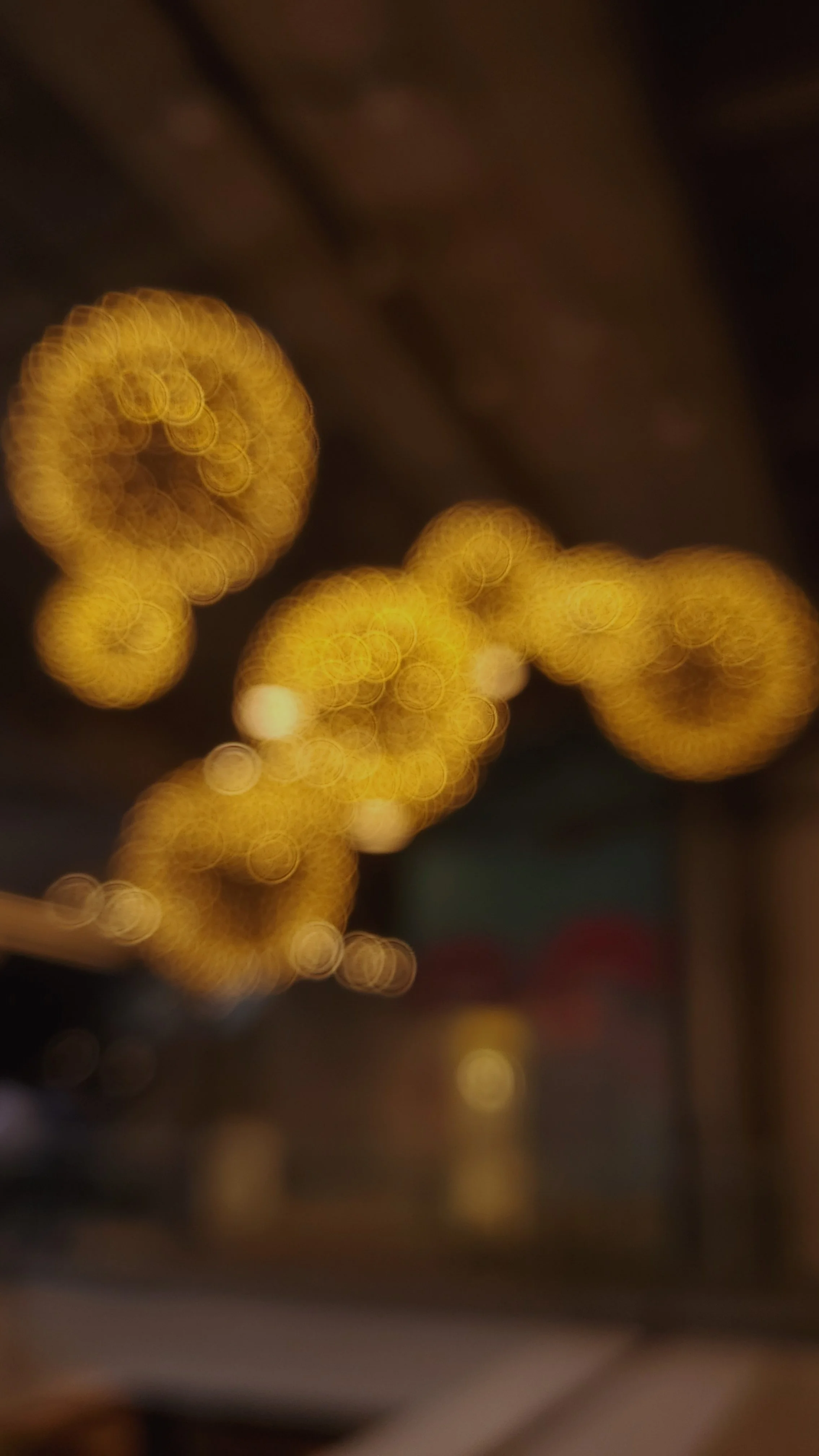Out of focus image with warm yellow and orange circular lights, possibly festive or decorative lighting.
