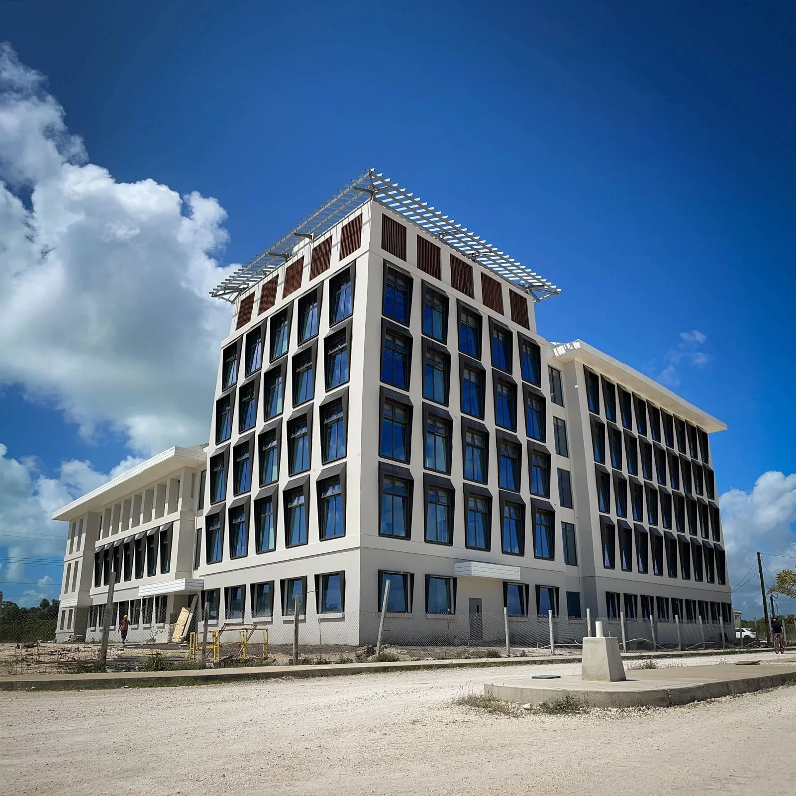 Modern multi-story building under construction with a blue sky and scattered clouds in the background