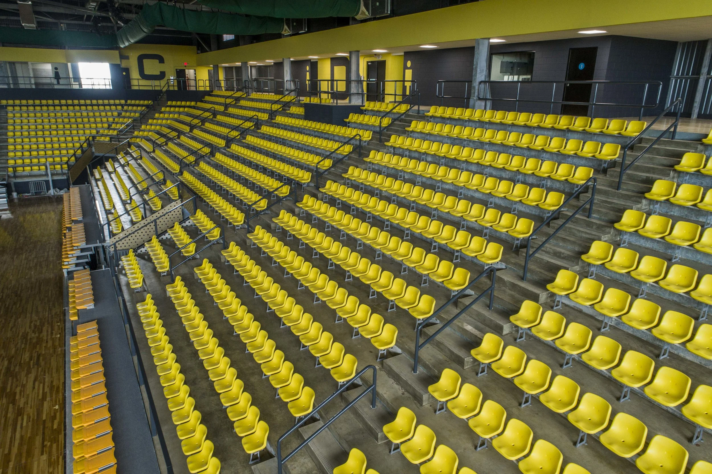 Interior of an arena or stadium with rows of yellow seats and a yellow and black color scheme.