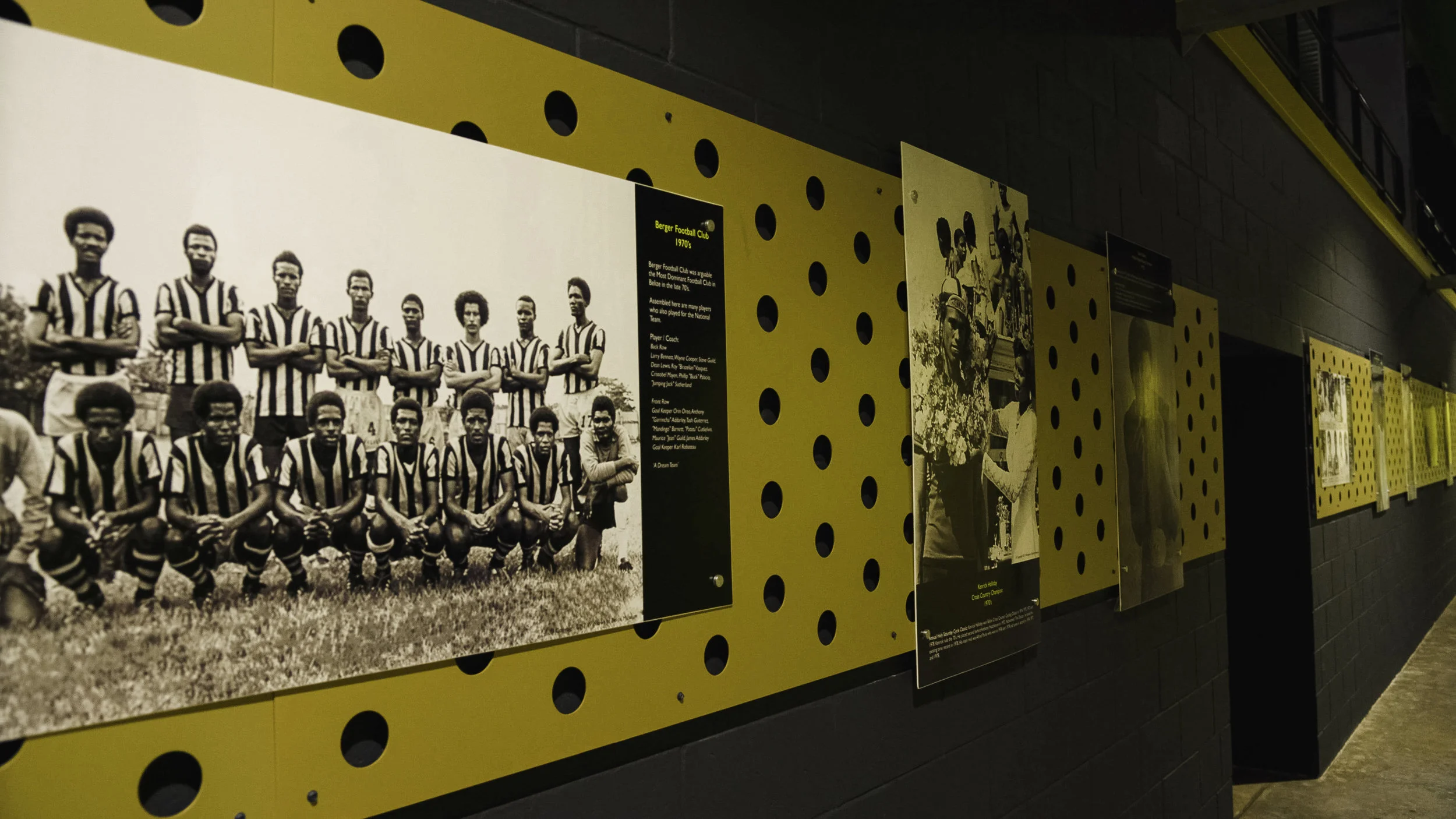 Black and white historical soccer team photo on display at a museum, with informational plaques and yellow perforated background panels.