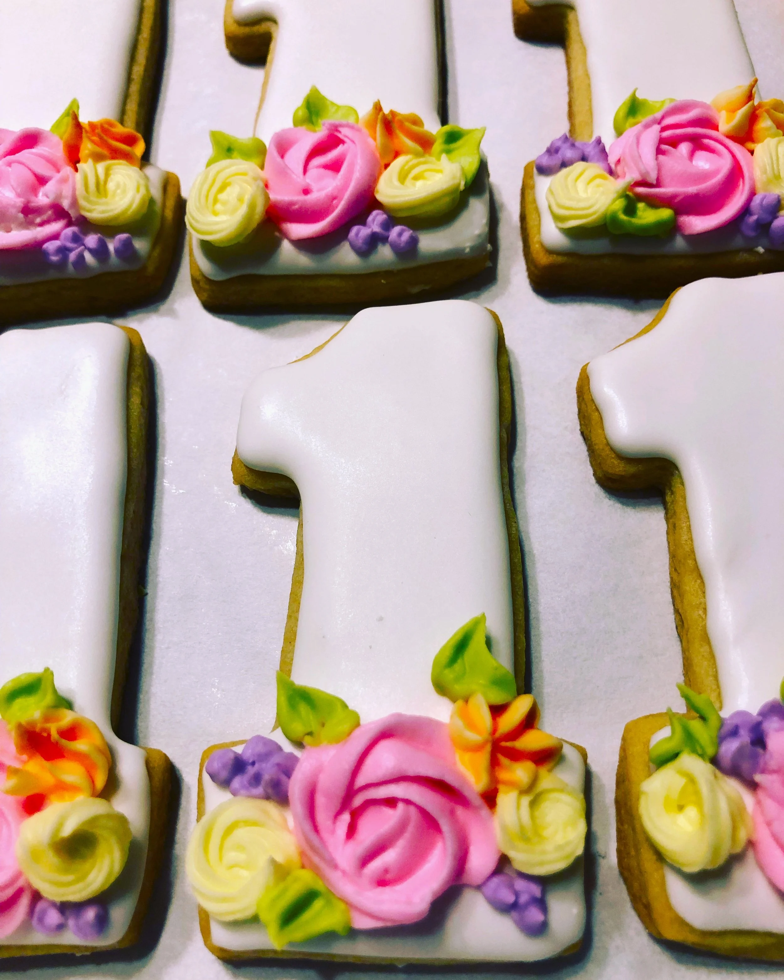 Number one shaped cut-out cookie decorated with pastel floral royal icing