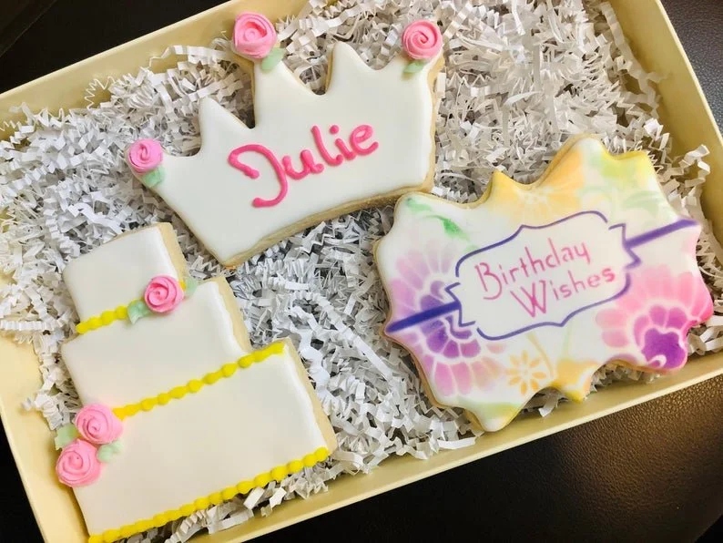 Birthday cut-out cookie trio featuring a decorated cake, personalized crown, and floral message plaque, in gift box