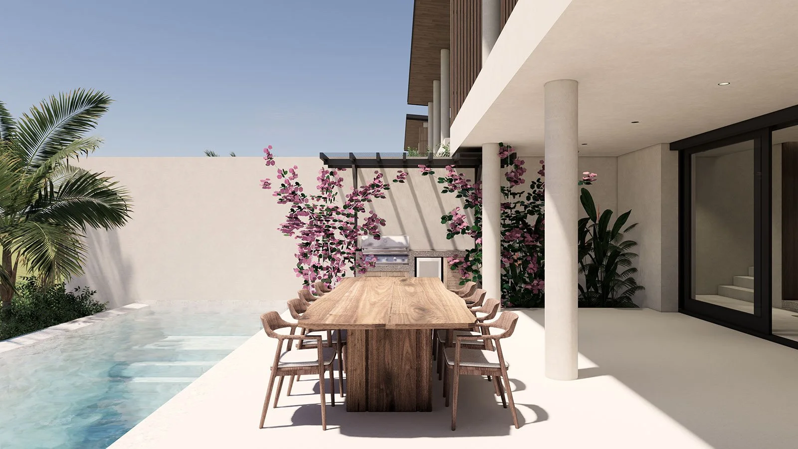 Modern outdoor patio with a large wooden dining table, surrounded by ten chairs, next to a swimming pool with a garden wall covered in pink flowering plants, and a built-in grill area in the background.