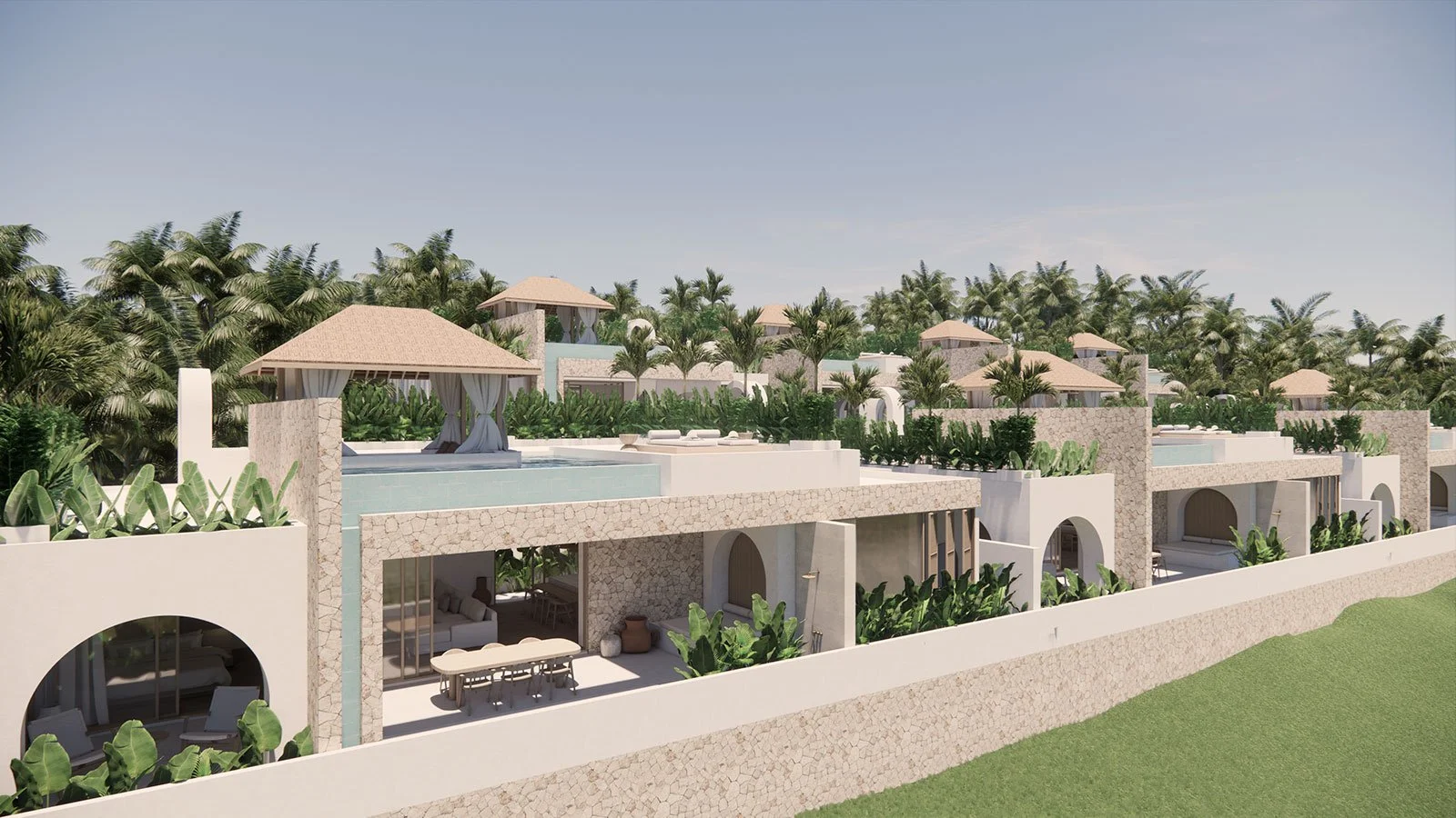 A modern luxury residential complex with multiple villas, outdoor shaded lounge areas, lush greenery, and a stone wall, set against a backdrop of tropical palm trees under a clear sky.