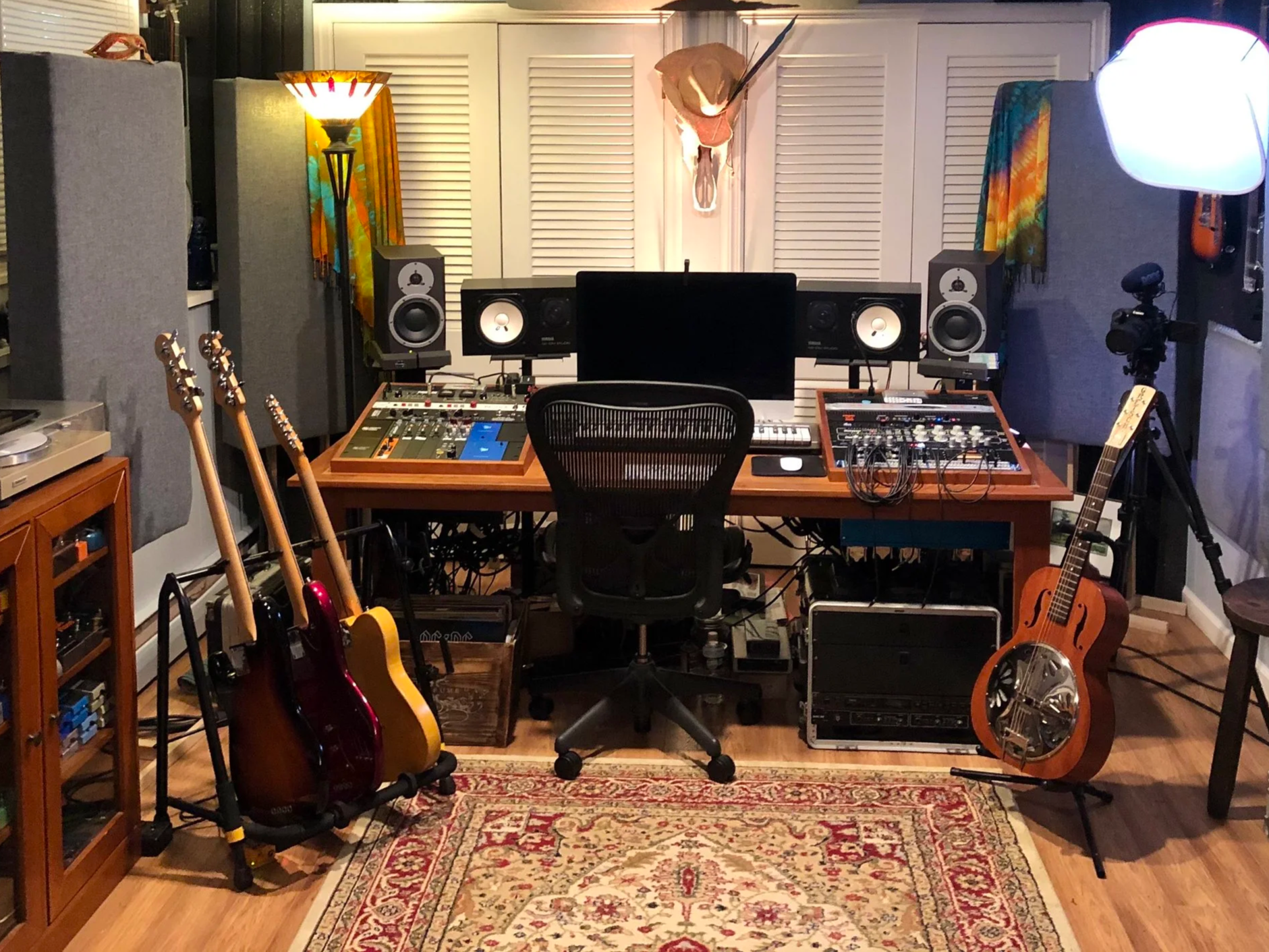 Recording studio with musical instruments, audio equipment, and a patterned area rug.