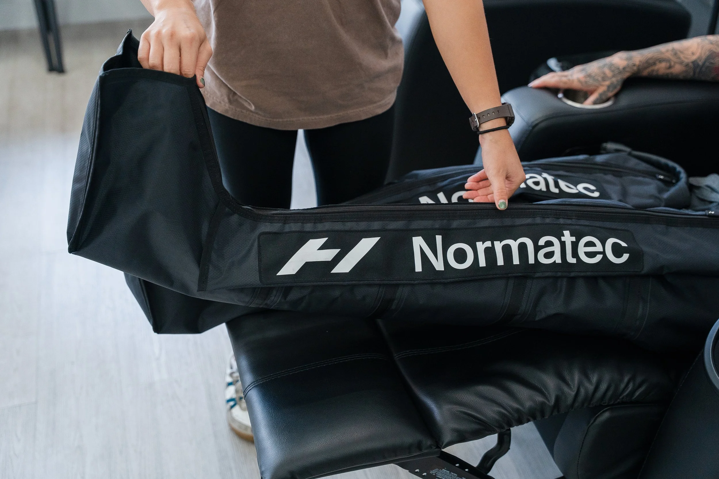 Person packing a travel bag labeled 'Normatec' with another bag in the background.