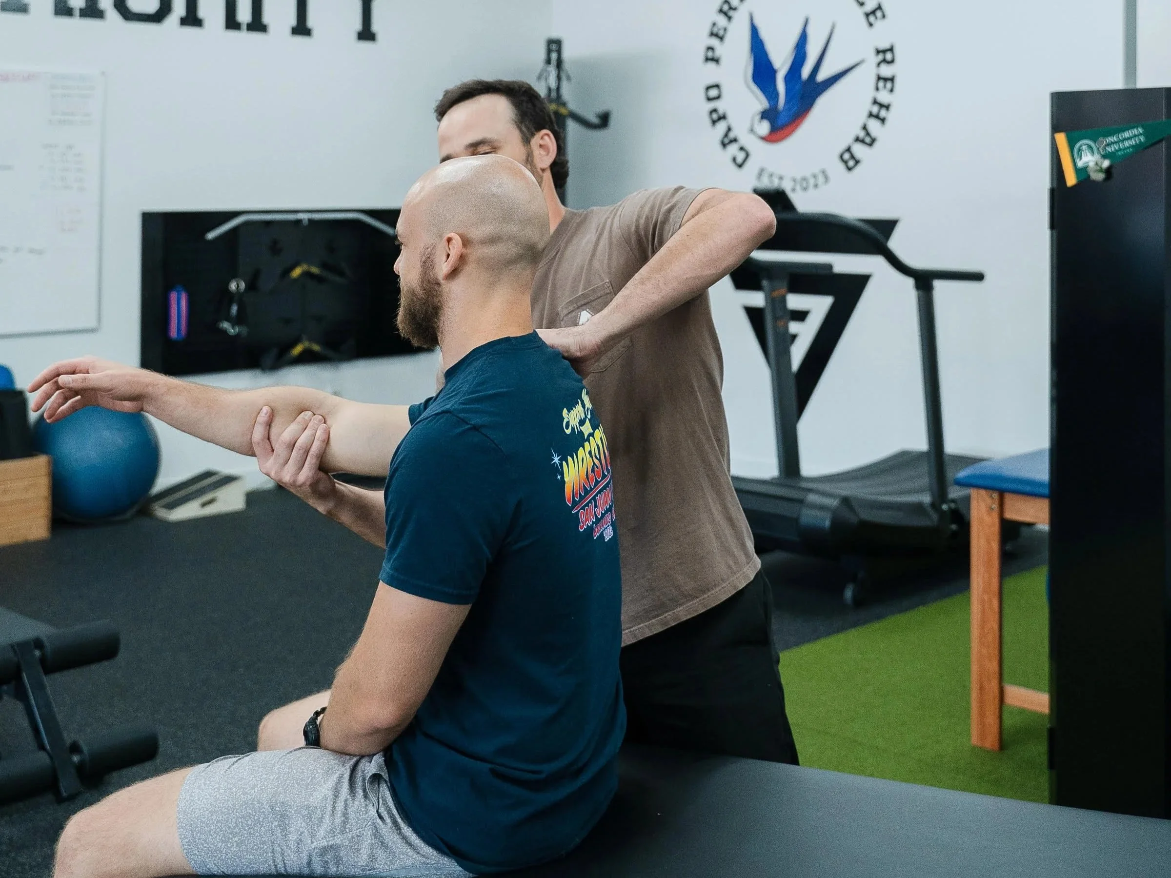 A person receiving shoulder massage from a therapist in a fitness or therapy center.