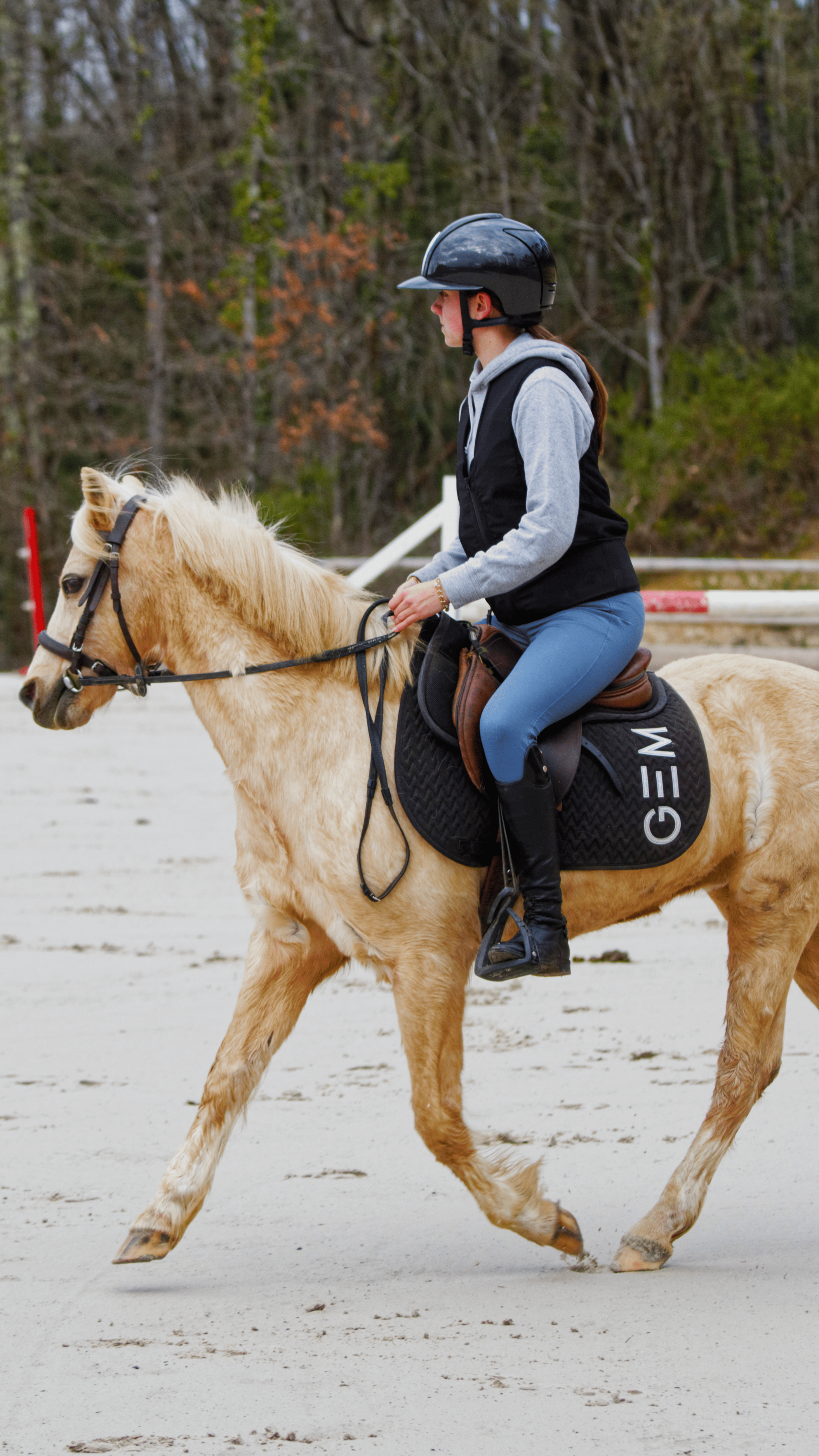Femme en casque de protection faisant du cheval dans une carrière d'équitation.