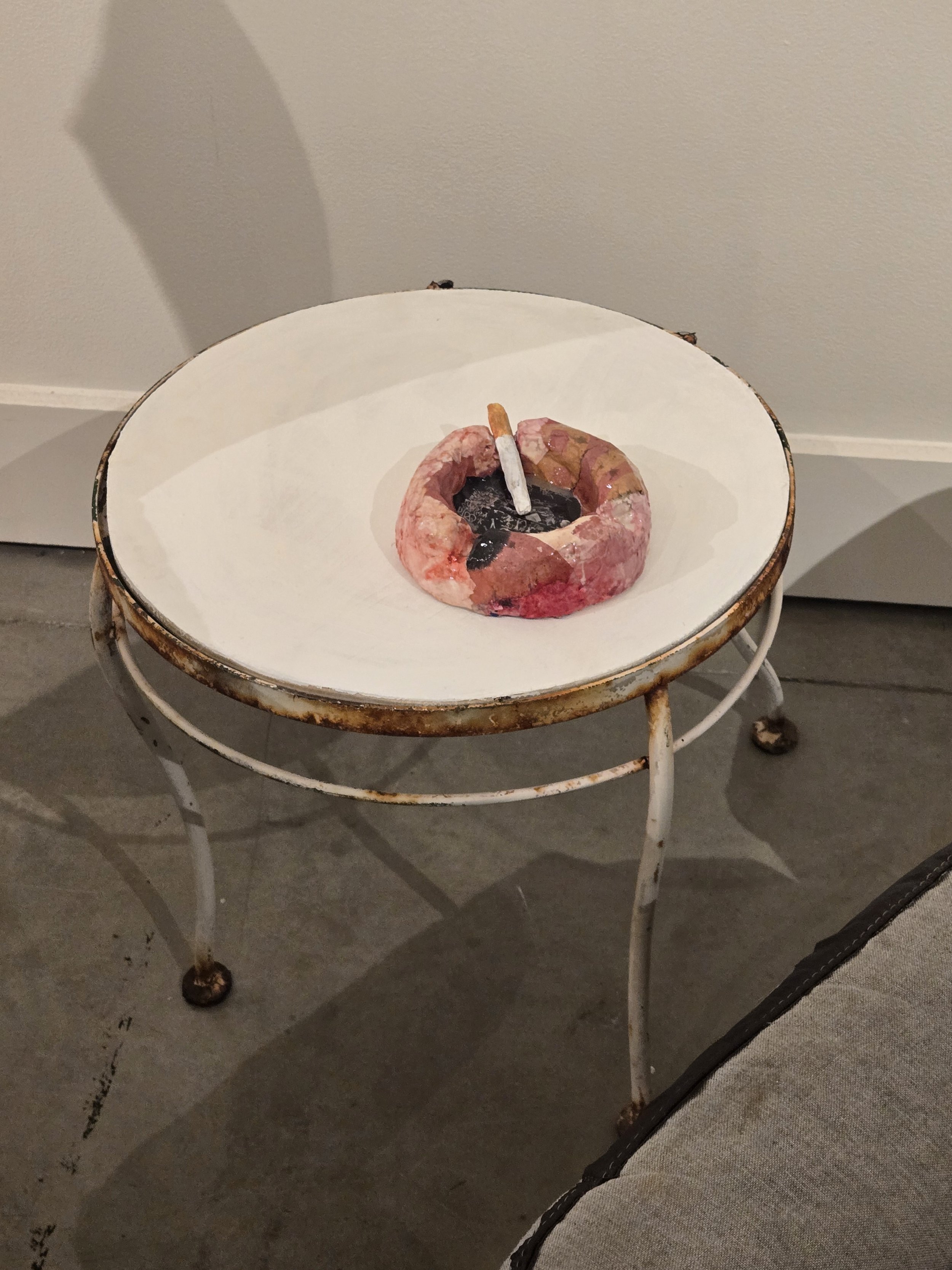 broken table with paper clay ashtray and cigarette