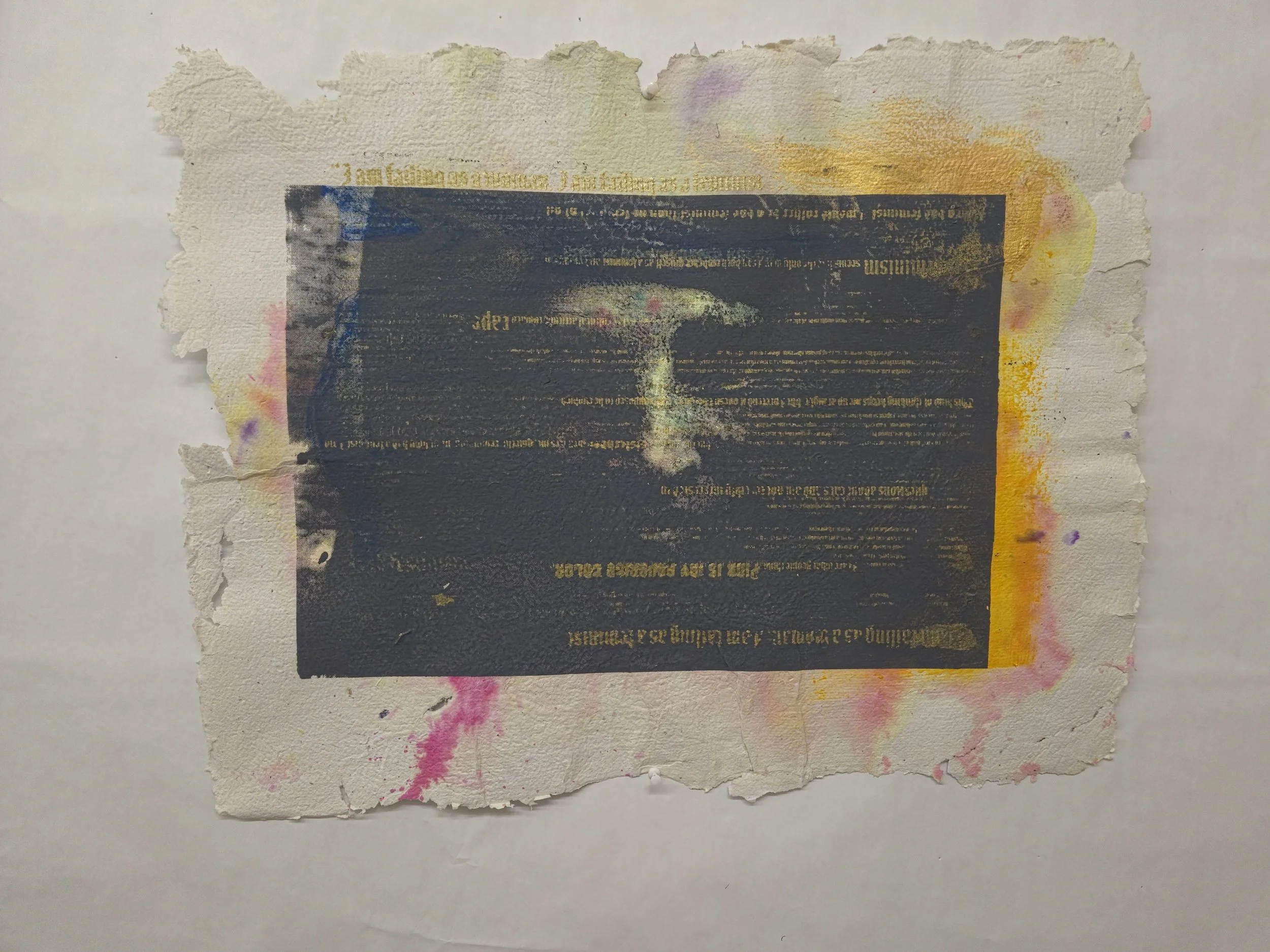 A torn piece of paper with a partially visible printed document that is dark with gold and white text, surrounded by pink, yellow, and purple paint splatters on a white background.
