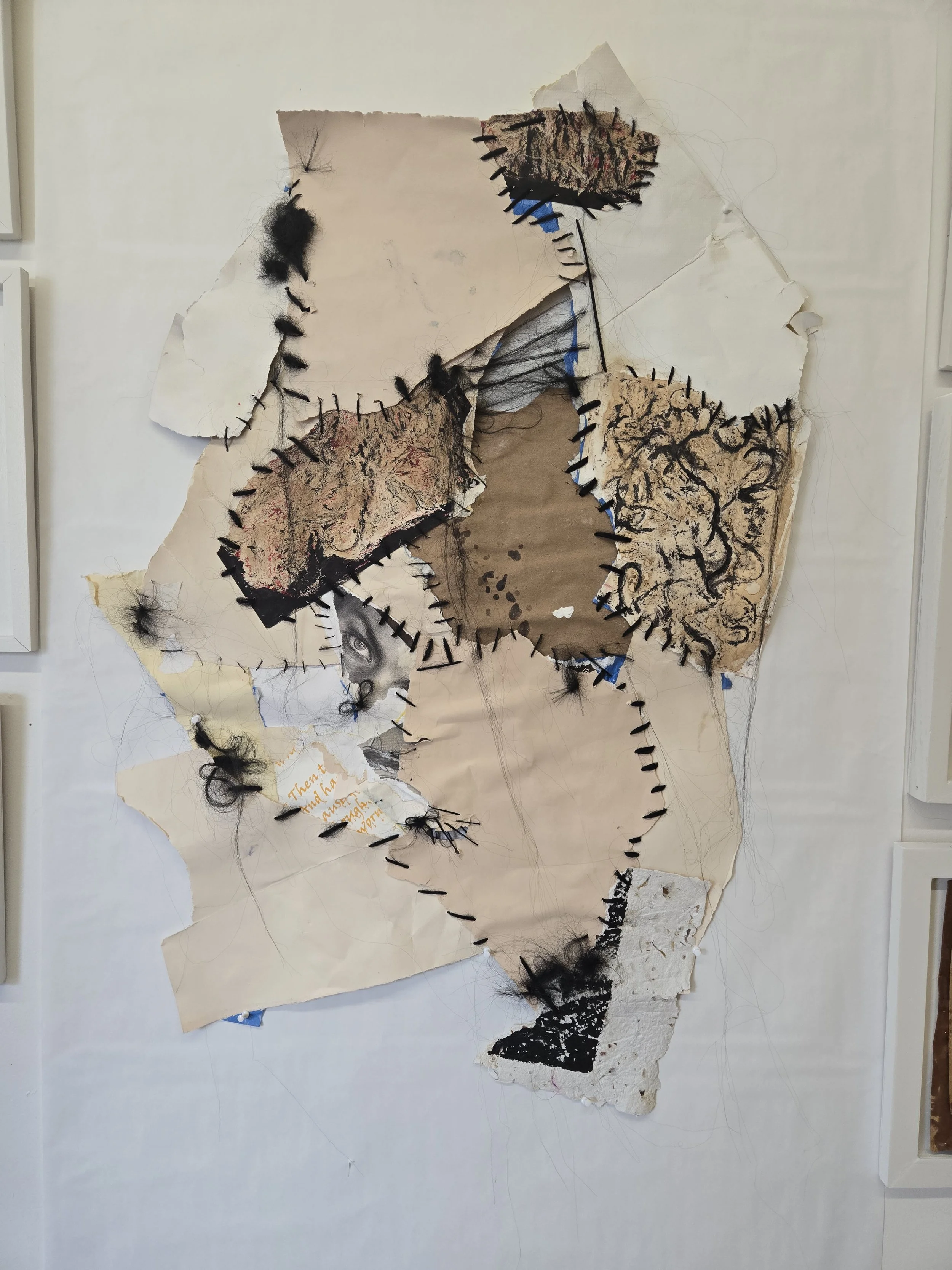 Mixed media collage artwork with torn paper, sketches, and textiles, sewn together with black thread, featuring a partially visible eye, abstract textures, and handwritten notes.