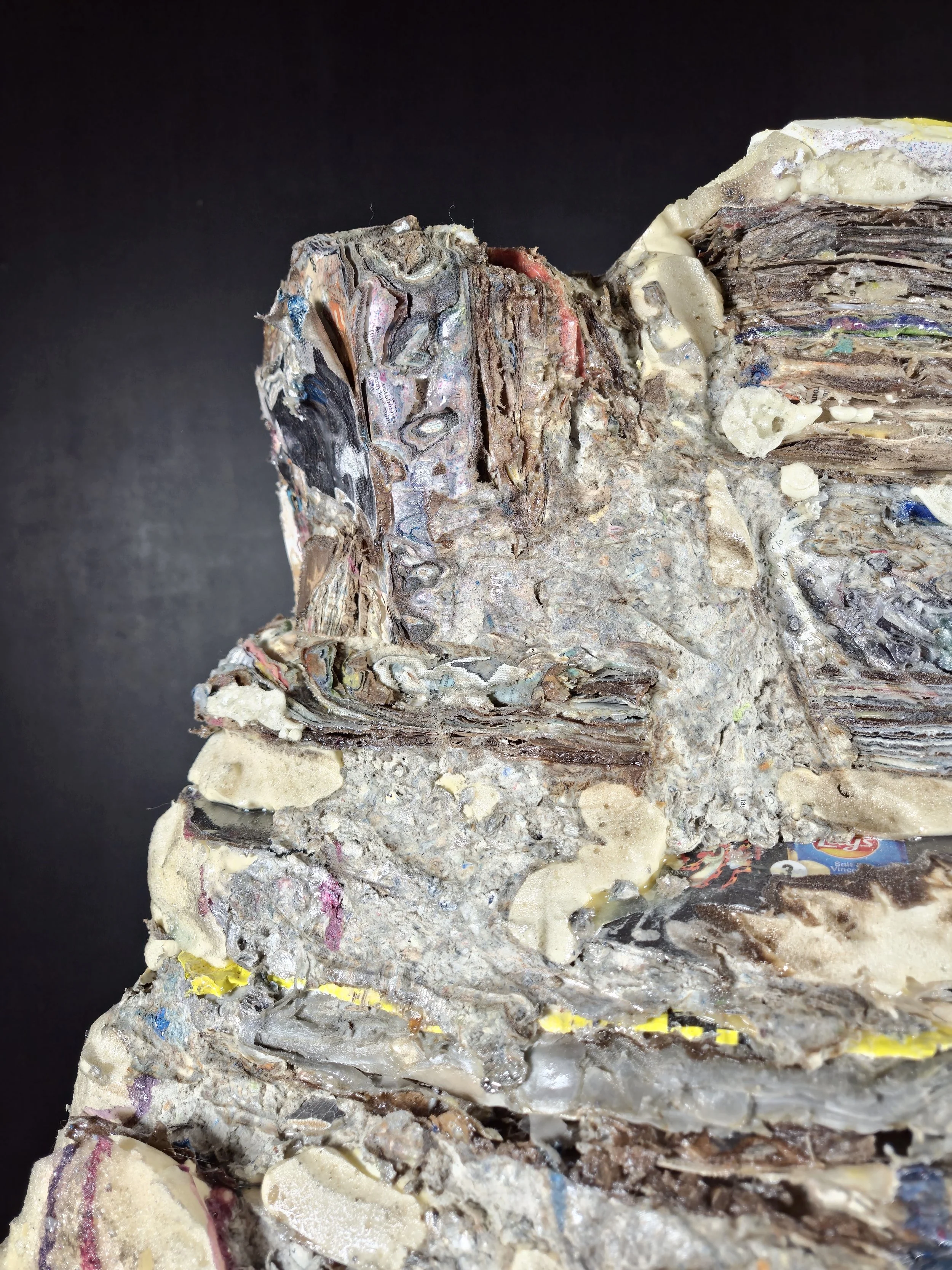 Close-up of a compressed boulder of mixed paper and plastic waste.