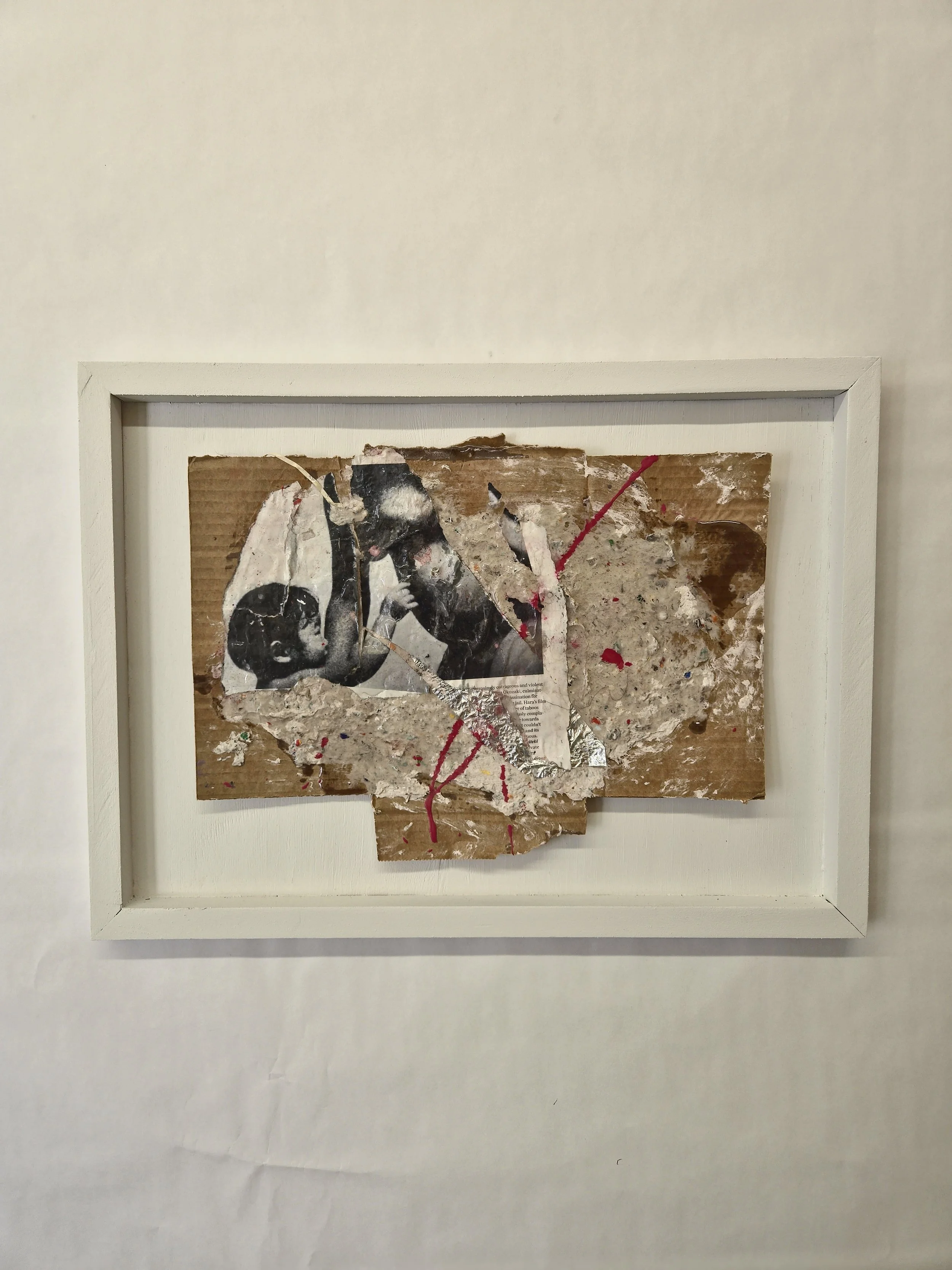 Mixed media artwork featuring a torn photograph of two people, with added paint splatters and textures, framed on a white background.