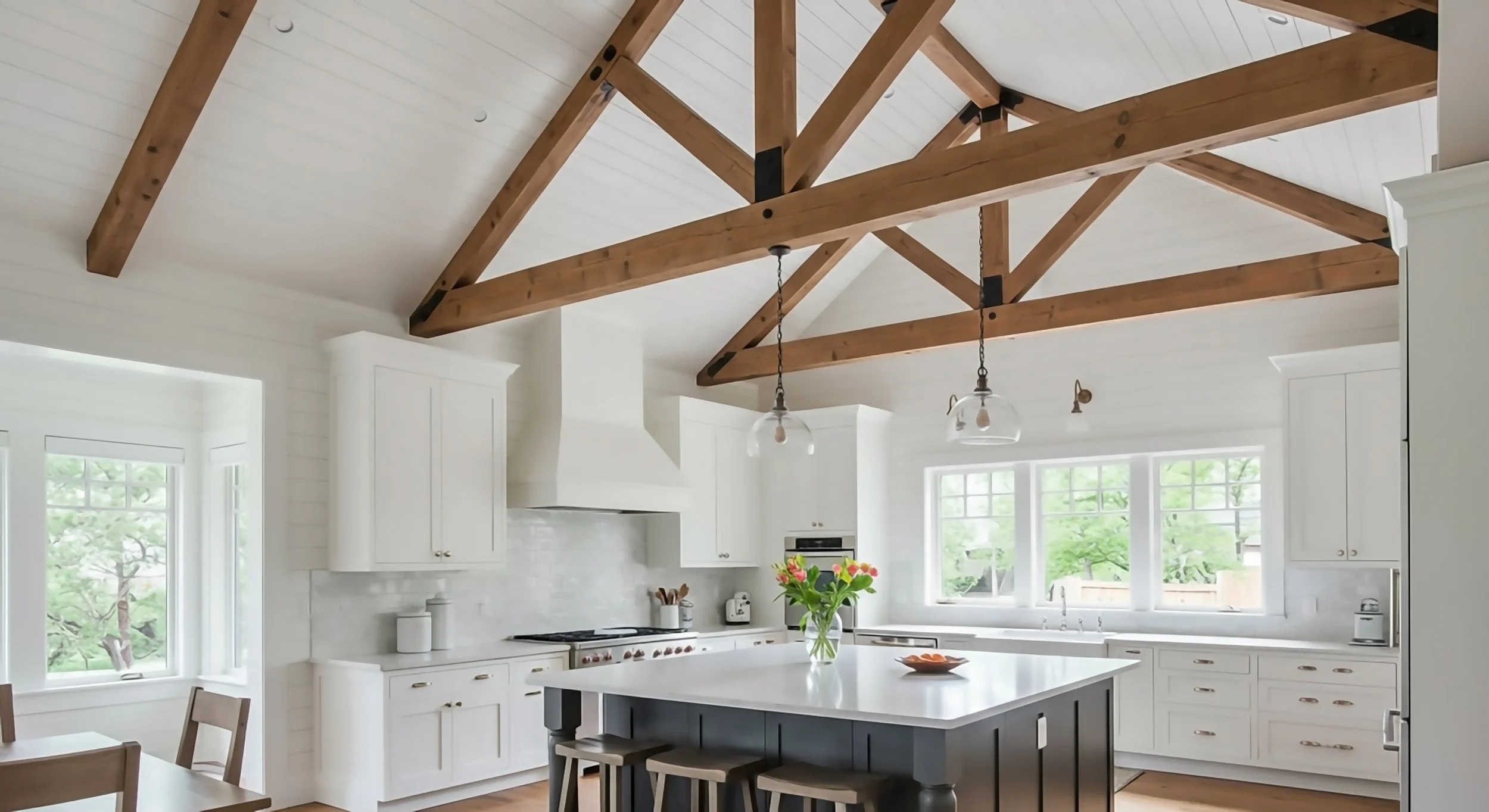 Custom luxury kitchen featuring exposed structural wood ceiling trusses, quartz island, and white inset cabinetry.