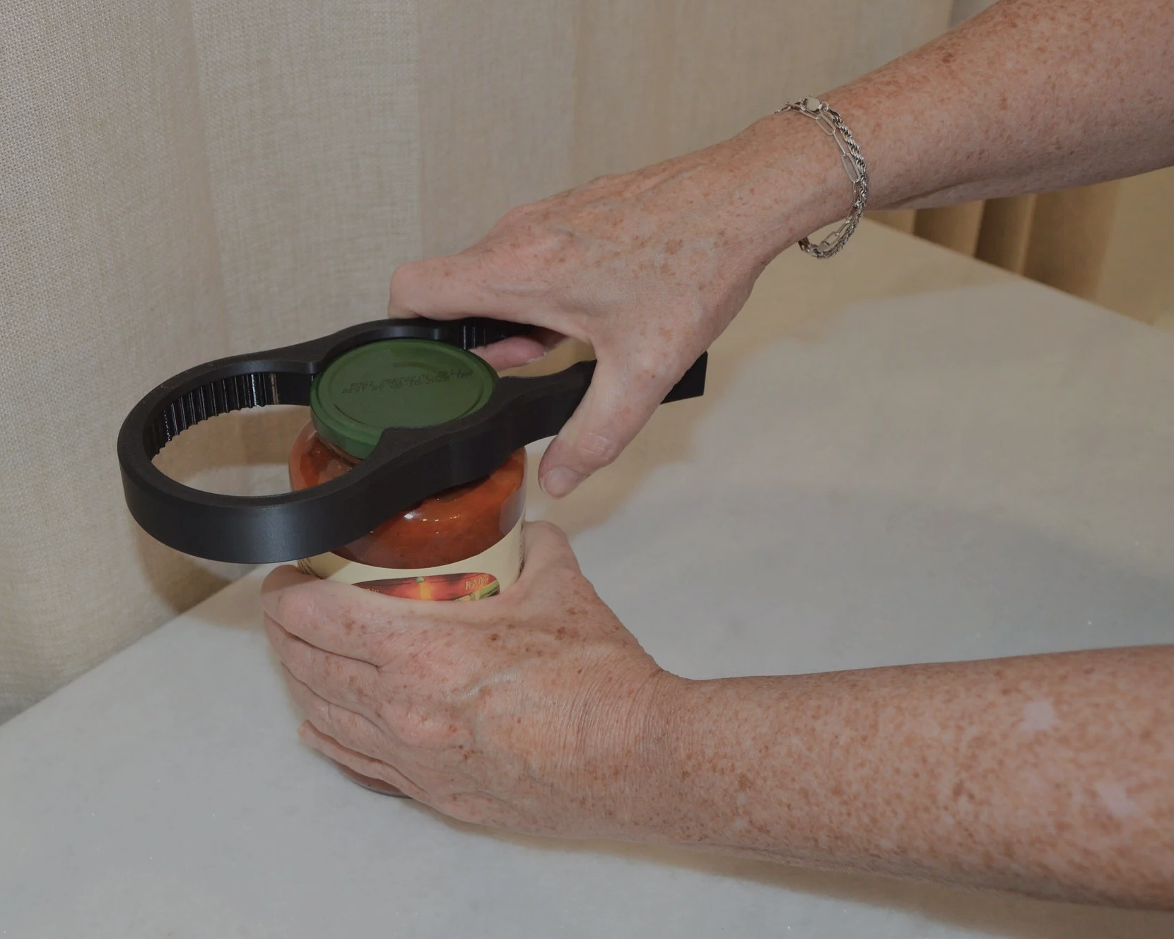A person's hands using a bottle opener to open a jar of peaches.
