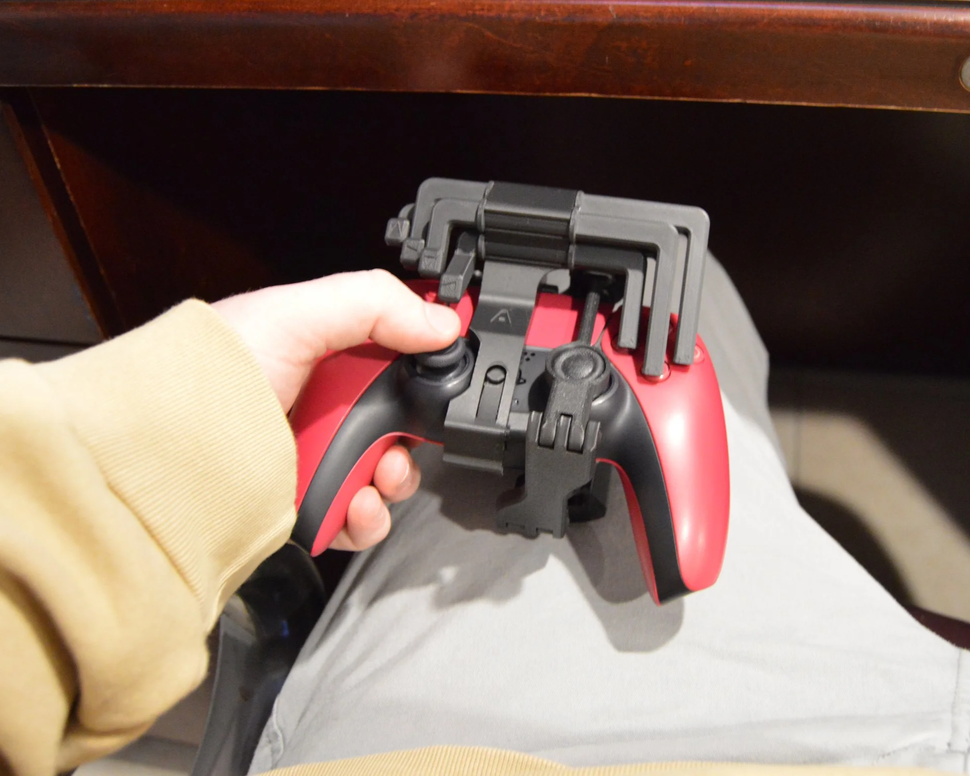 A person holding a gaming controller with several L-shaped Allen keys clipped onto it, with a wooden table in the background.
