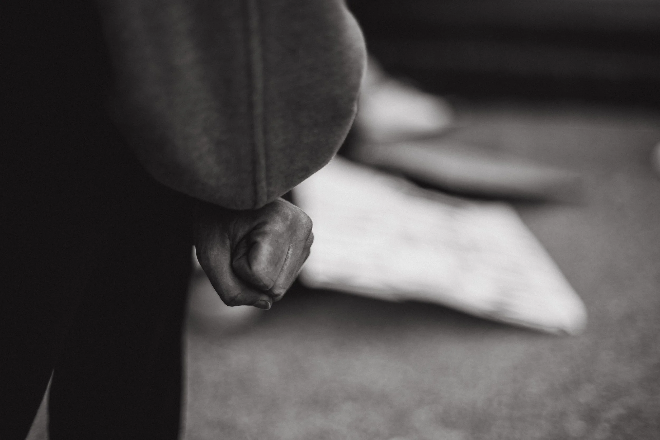 Close-up of a person's clenched fist held close to their body in grayscale.