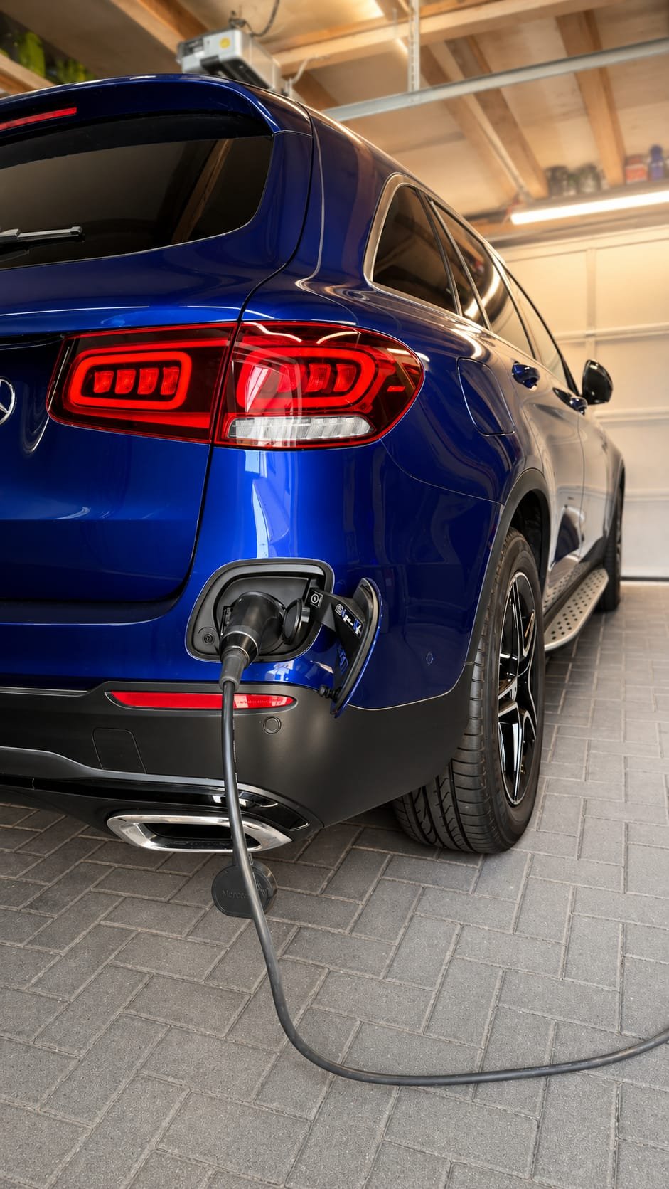 Ein blauer SUV wird in einer Garage mit einem Ladekabel für Elektroautos verbunden.